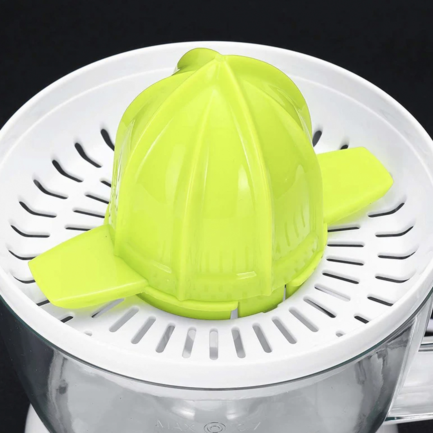 Primo piano di uno spremiagrumi. Una base bianca con un cono di spremitura verde e una parte superiore bianca perforata. Lo sfondo è nero.
