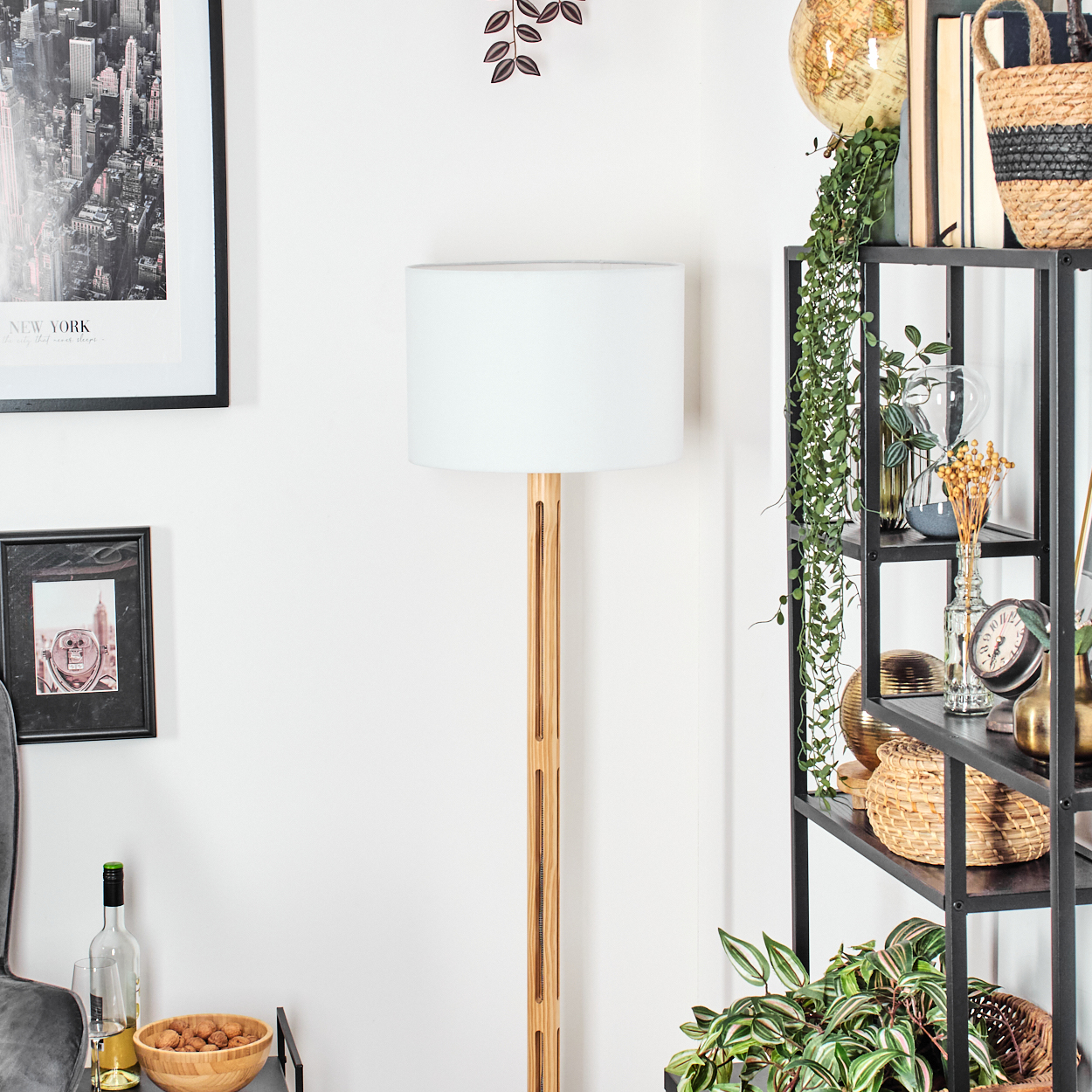 Ein Rauminterieur mit einer Lampe, Regalen und verschiedenen dekorativen Gegenständen. Ein New York-Poster hängt an der Wand.