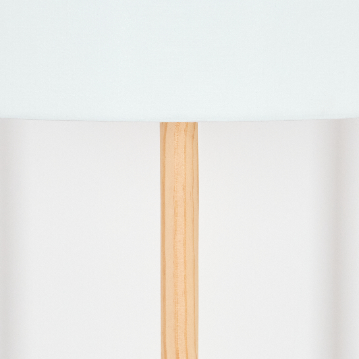 Nahaufnahme einer Lampe. Hellblauer Lampenschirm über einem Holzpfahl. Der Hintergrund ist weiß.