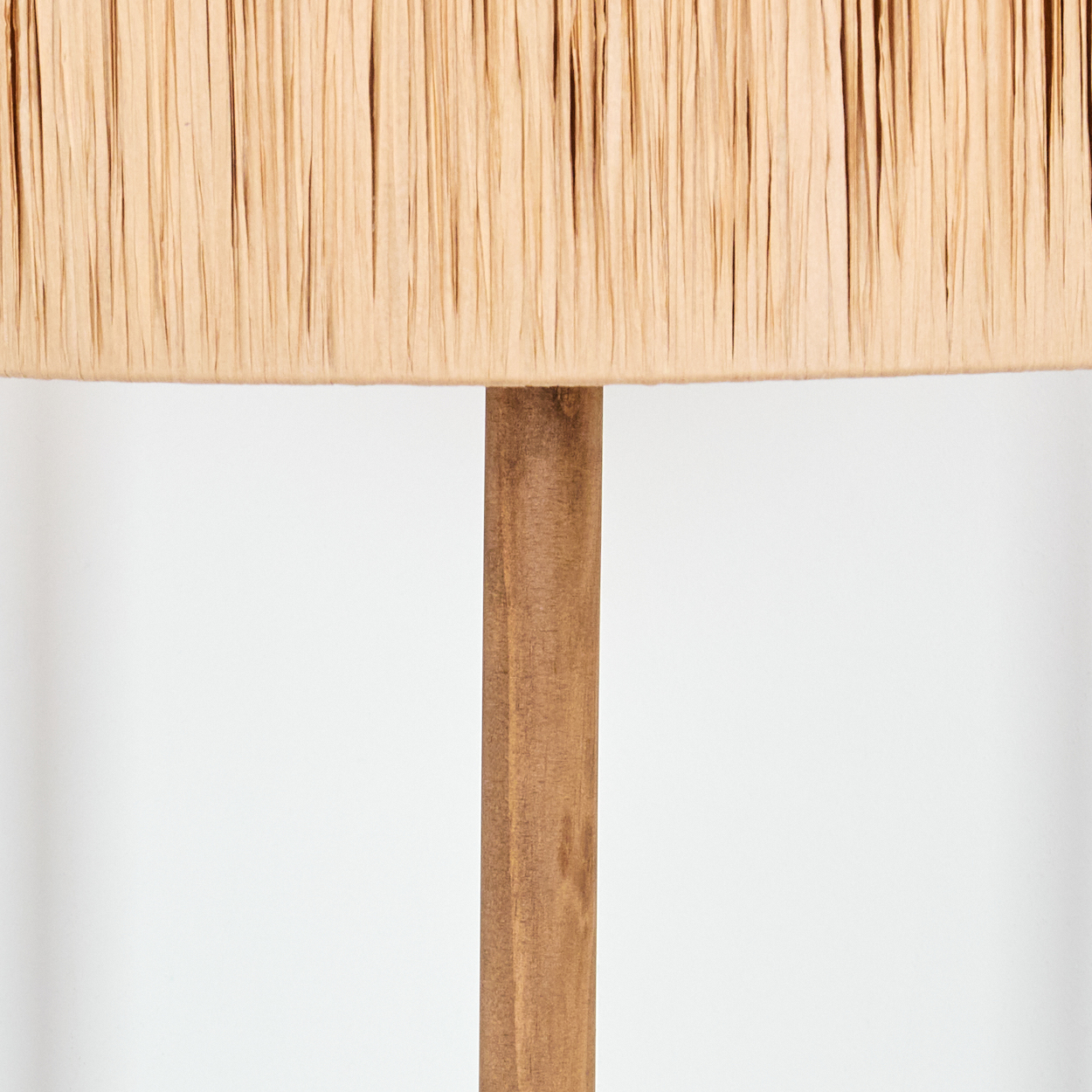 Nahaufnahme einer Lampe. Beigefarbener Lampenschirm mit vertikalen Linien. Brauner Holzpfahl in der Mitte. Weißer Hintergrund.