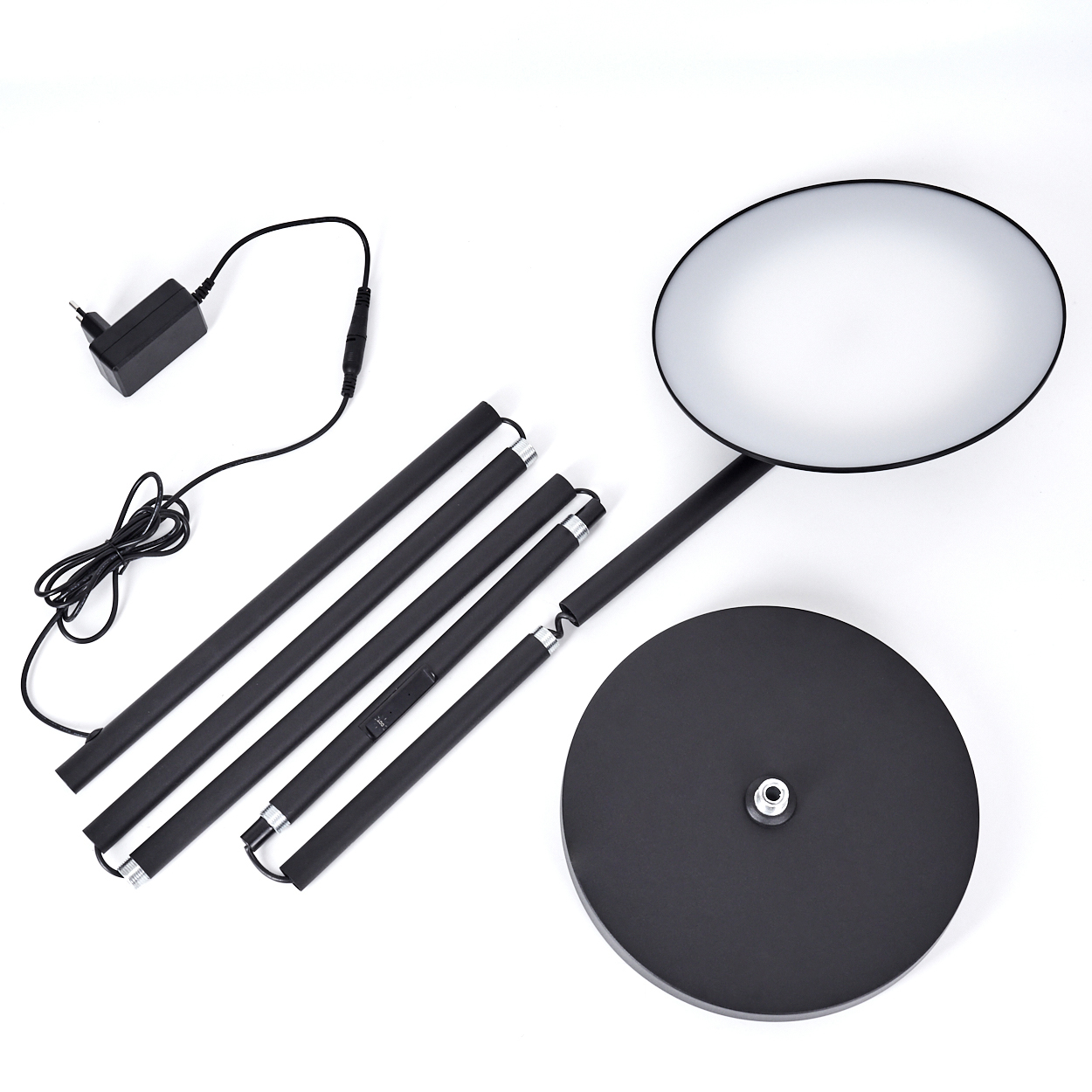 Zerlegte schwarze Stehlampe. Teile sind Fuß, Stiel, Licht und Netzteil. Alles auf weißem Hintergrund.