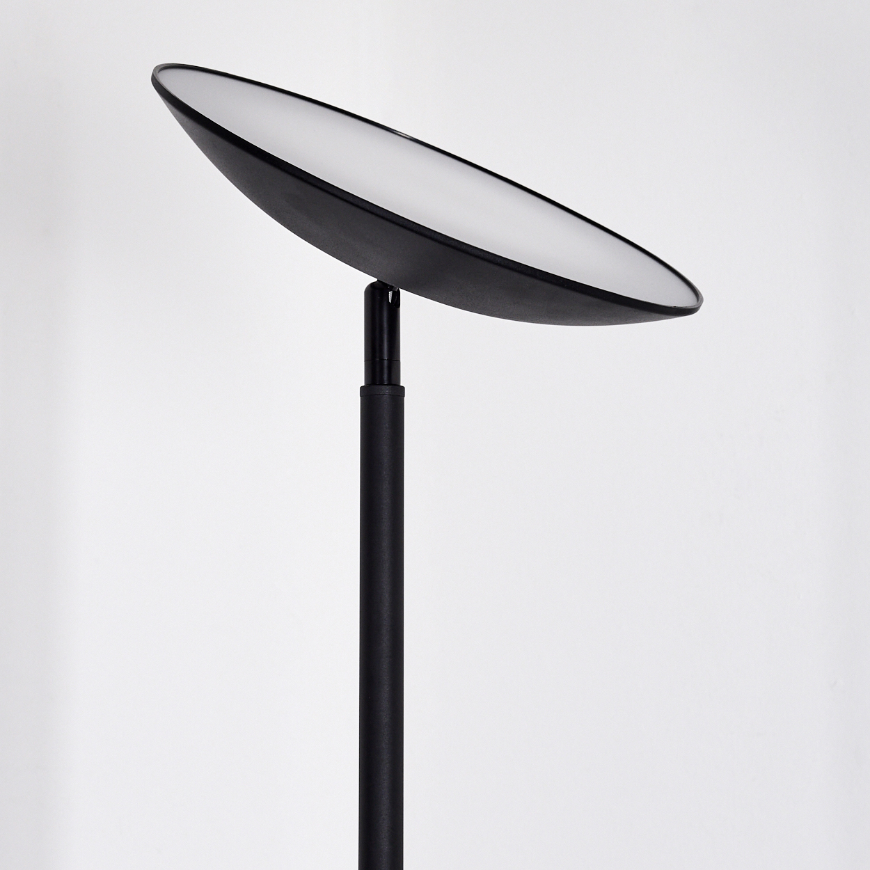 Eine moderne schwarze Lampe mit einem breiten, flachen, ovalen Lampenschirm. Die Lampe steht auf einem schwarzen Pfosten vor weißem Hintergrund.