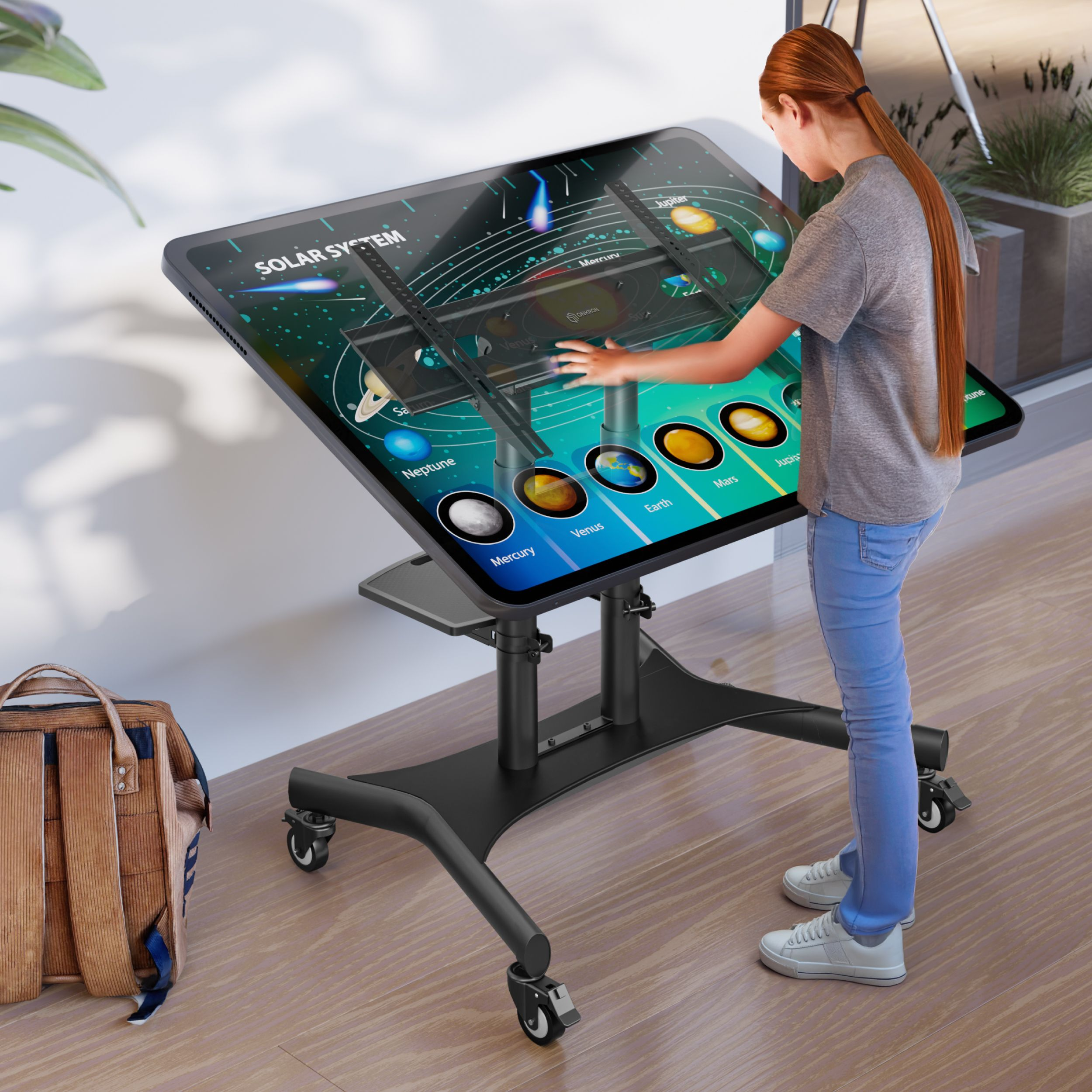 Una ragazza interagisce con un display del sistema solare su un tavolo touchscreen. Uno zaino è appoggiato lì vicino.
