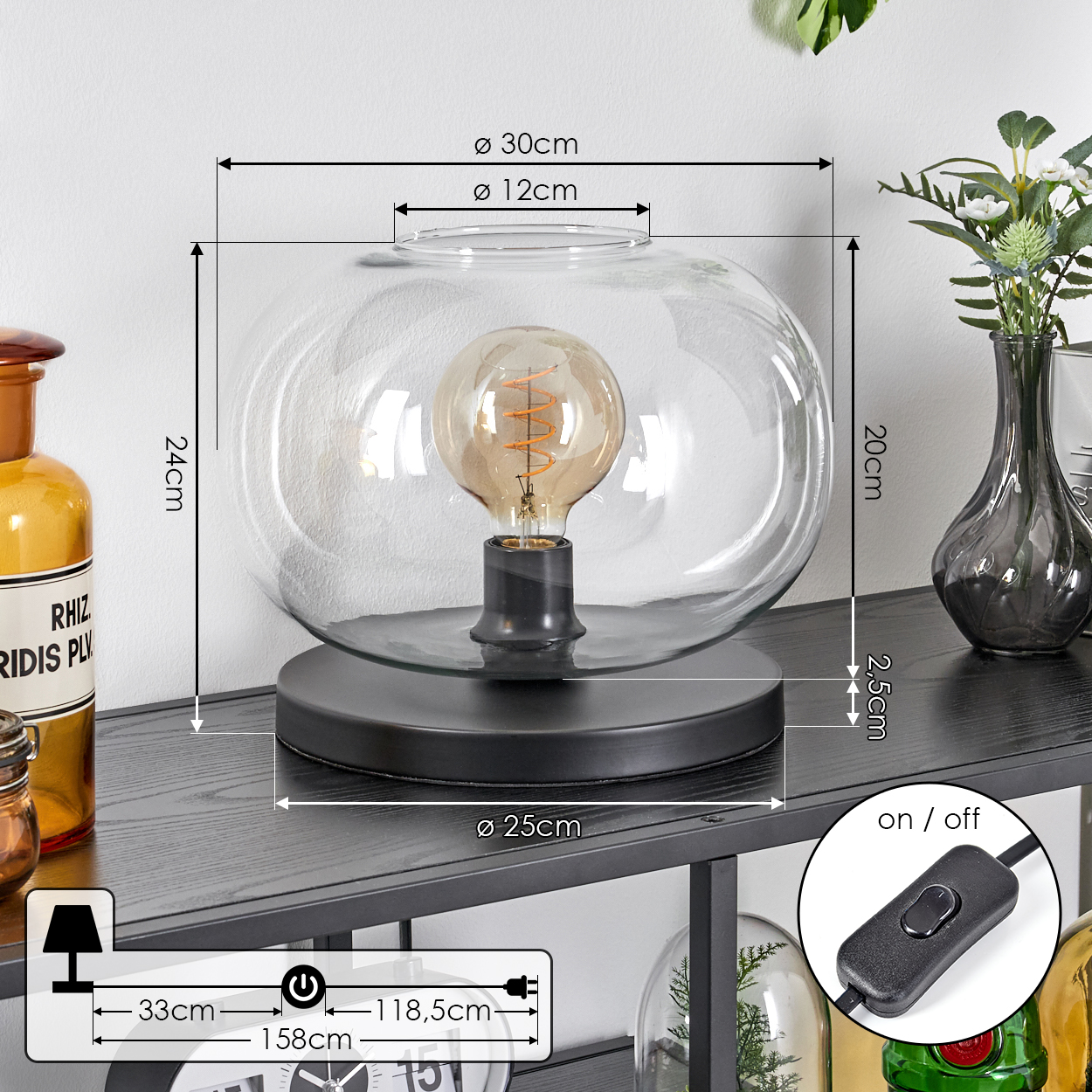 Eine moderne Lampe mit rundem Glasschirm und sichtbarer Glühbirne auf einem schwarzen Regal. Maße werden angezeigt.