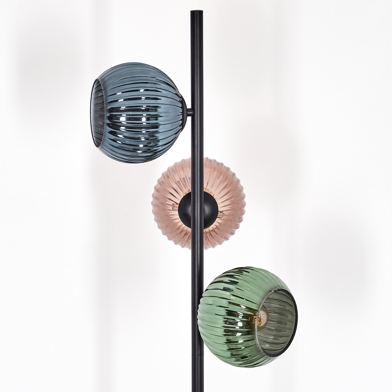 Eine moderne Stehlampe mit drei Glasschirmen in Türkis, Rosa und Grün. Die Schirme sind gerippt und kugelförmig, an einem schwarzen Pol.