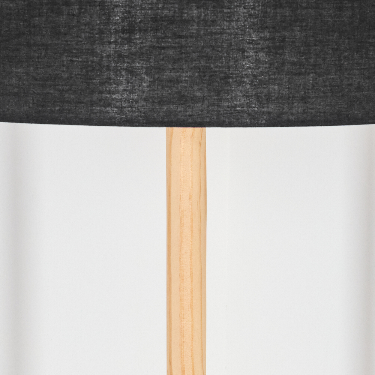 Eine Lampe mit schwarzem Lampenschirm und hellbraunem Holzpfahl vor schlichtem, weißem Hintergrund.