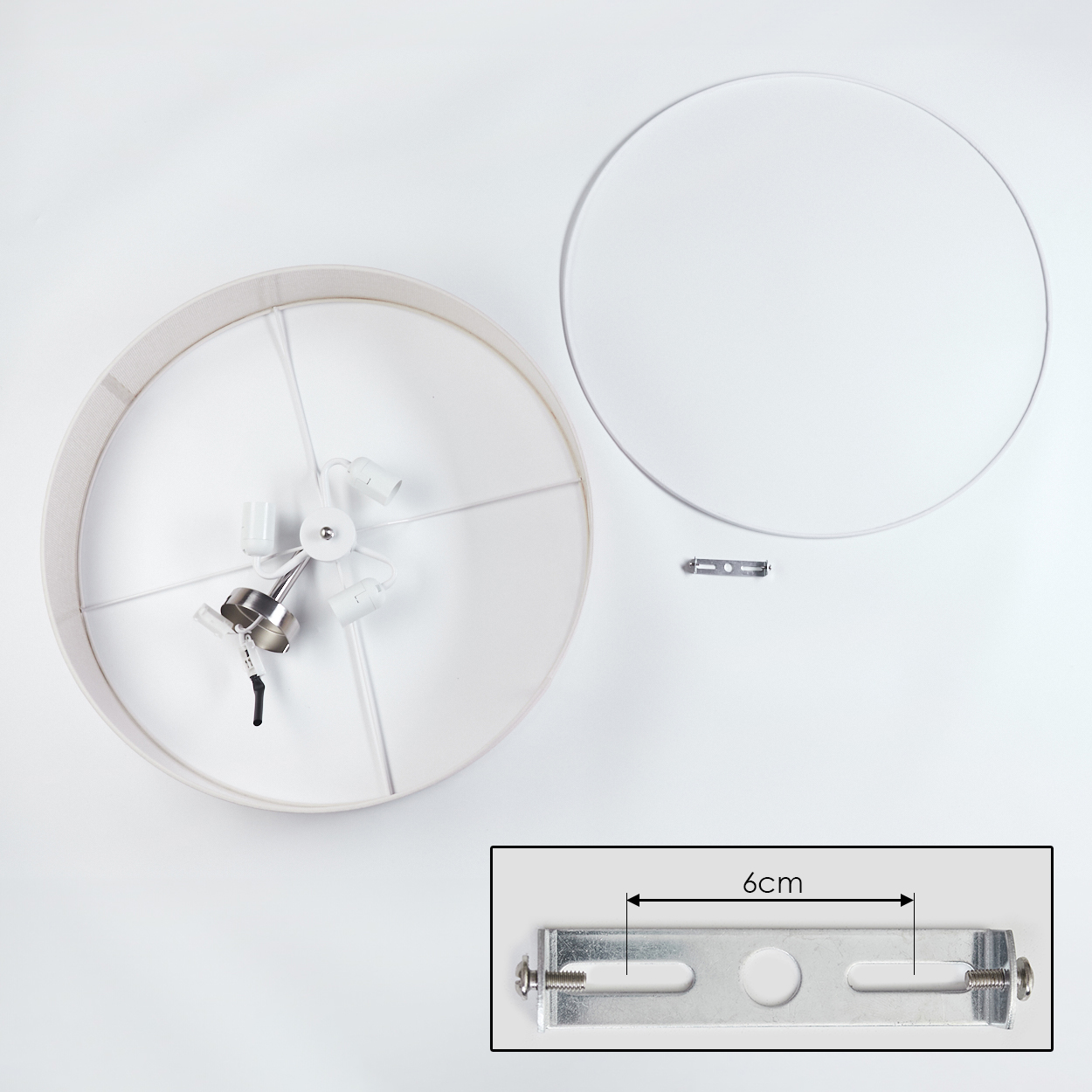 Draufsicht auf eine zerlegte Lampe. Lampenschirm, Lampenfassung und Halterung liegen auf weißer Oberfläche.