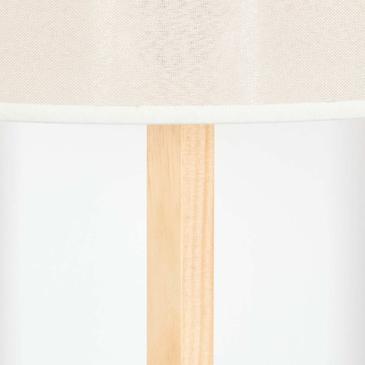 Nahaufnahme einer Lampe. Der Lampenschirm ist cremefarben und befindet sich über einer hellen Holzstütze. Der Hintergrund ist weiß.