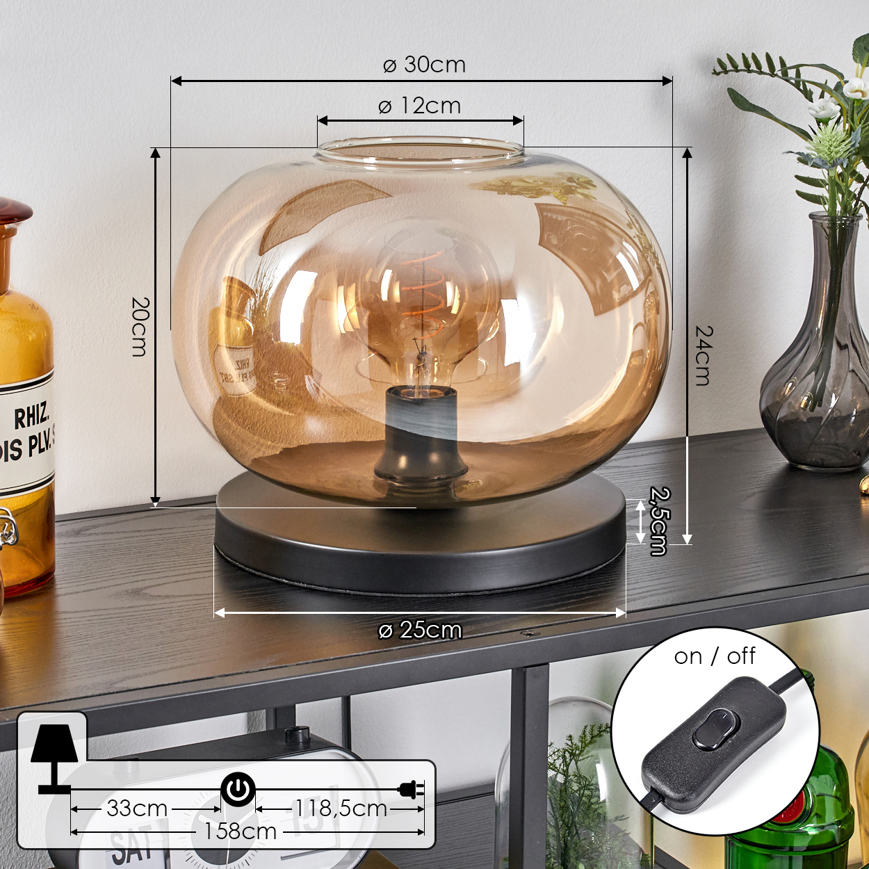 Eine dekorative Lampe mit rundem, bernsteinfarbenem Glasschirm und sichtbarer Glühbirne steht auf einem schwarzen Regal.