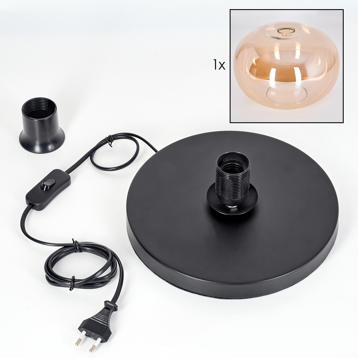 Eine zerlegte Lampe mit schwarzem Sockel, Fassung und Kabel. Ein Glasschirm ist in der Ecke. Teile liegen auf weißem Untergrund.