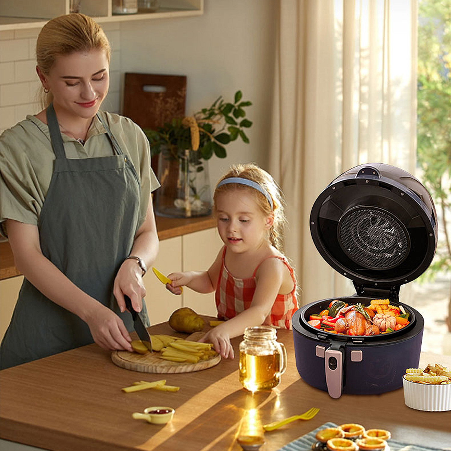 Una mujer y una niña están preparando comida. Una freidora de aire está abierta. Papas fritas y verduras son visibles en la mesa.