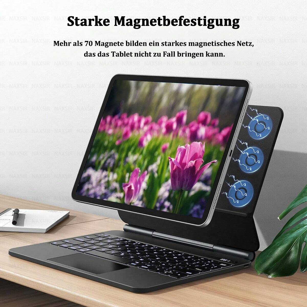 Tablet mit Tastatur, zeigt einen floralen Bildschirm. Das Tablet wird von einem magnetischen Ständer gehalten. Es gibt ein Notizbuch und einen Stift.