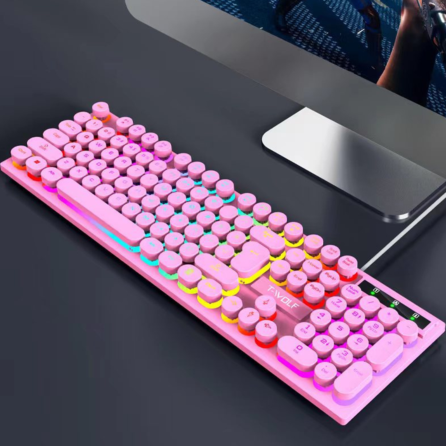 Eine rosa mechanische Tastatur mit runden Tasten liegt auf einem Schreibtisch. Die Tastatur hat einen bunten LED-Streifen. Ein Computermonitor ist im Hintergrund.