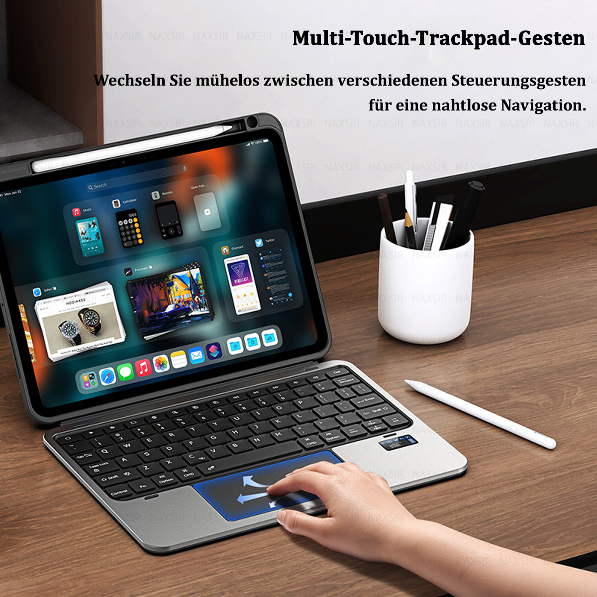 Ein iPad mit Tastatur und Stift auf einem Holztisch. Eine Hand benutzt das Trackpad. Apps sind auf dem Bildschirm sichtbar.