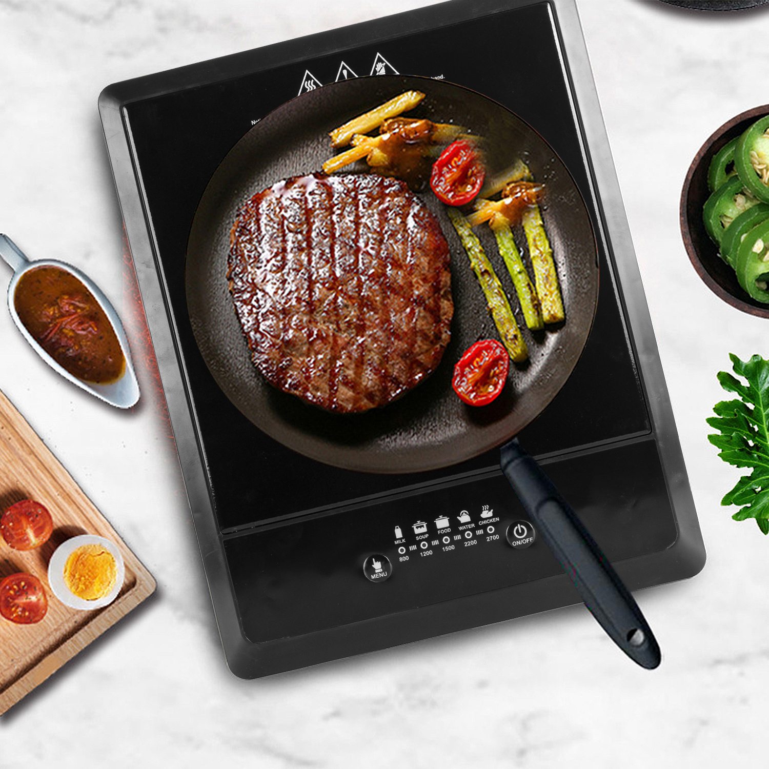 Ein Steak in einer Pfanne mit Spargel und Tomaten. Ein Teller mit Ei und Tomaten und eine Schüssel mit Jalapenos.