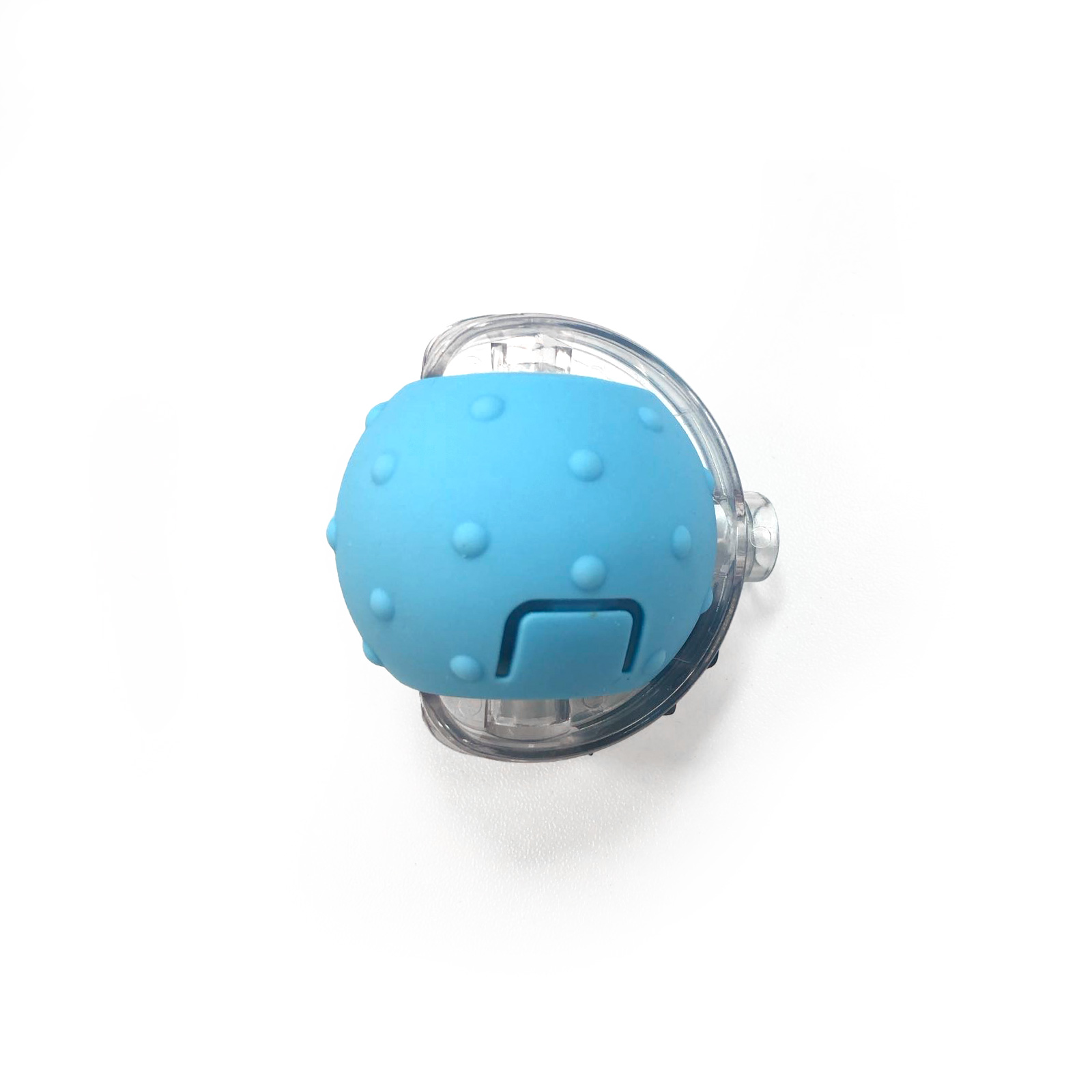 Una esfera azul con protuberancias está dentro de un soporte de plástico transparente. Se encuentra sobre una superficie blanca.