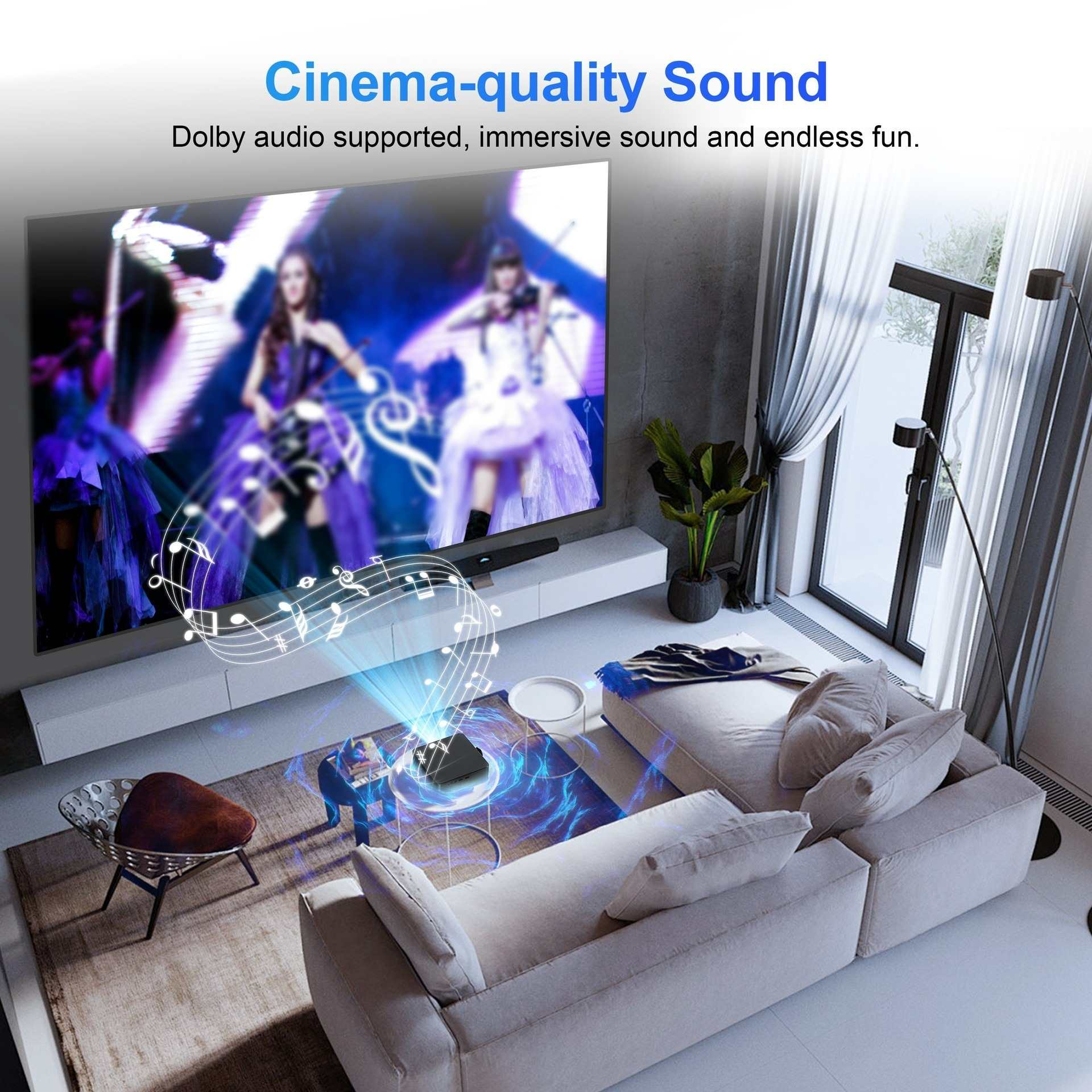 Ein Wohnzimmer mit einem großen Bildschirm, der ein Konzert zeigt. Auf dem Tisch steht ein Projektor und es gibt ein Sofa.