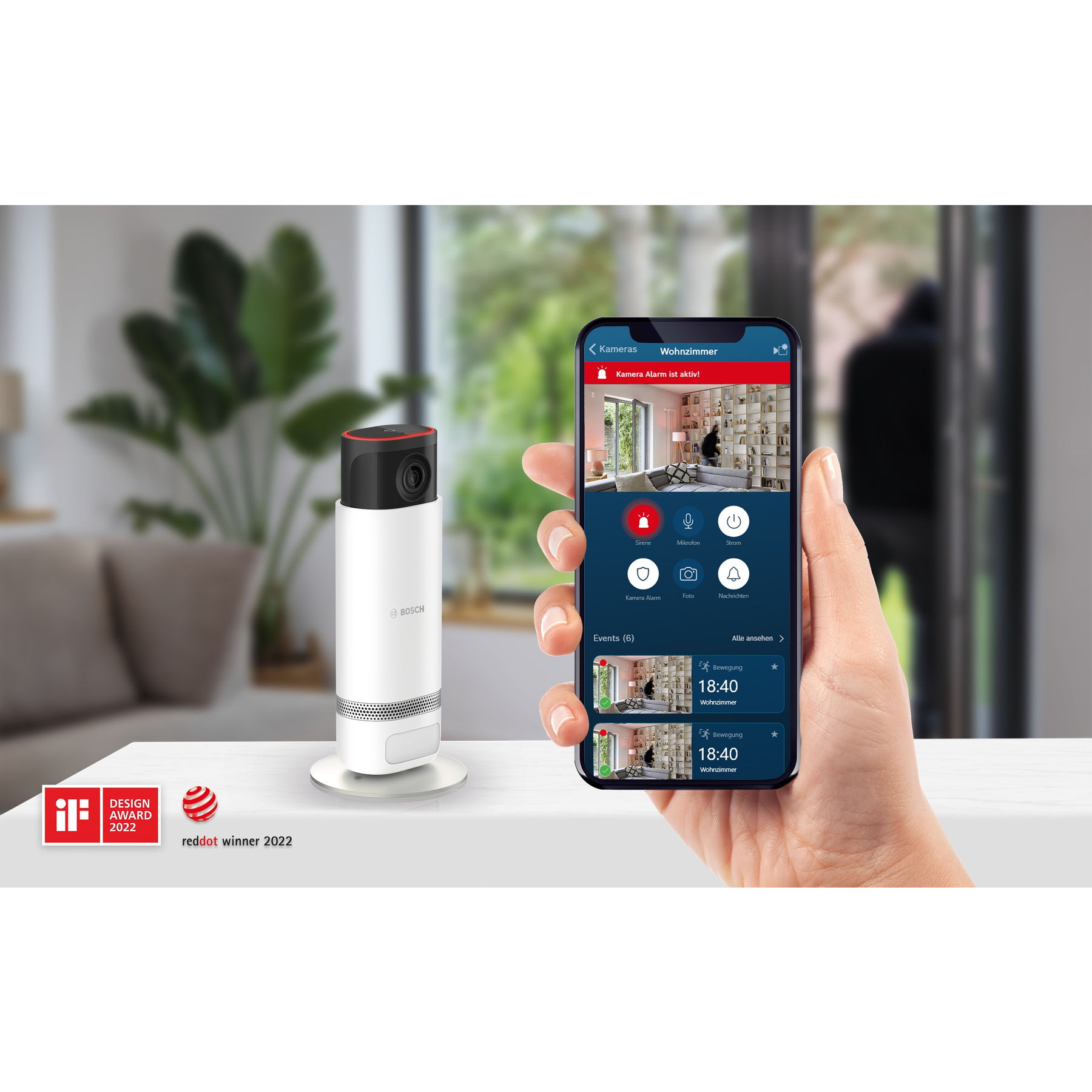 Eine Hand hält ein Telefon mit einer Sicherheitskamera-App. Links eine weiße Sicherheitskamera. Red Dot Award.