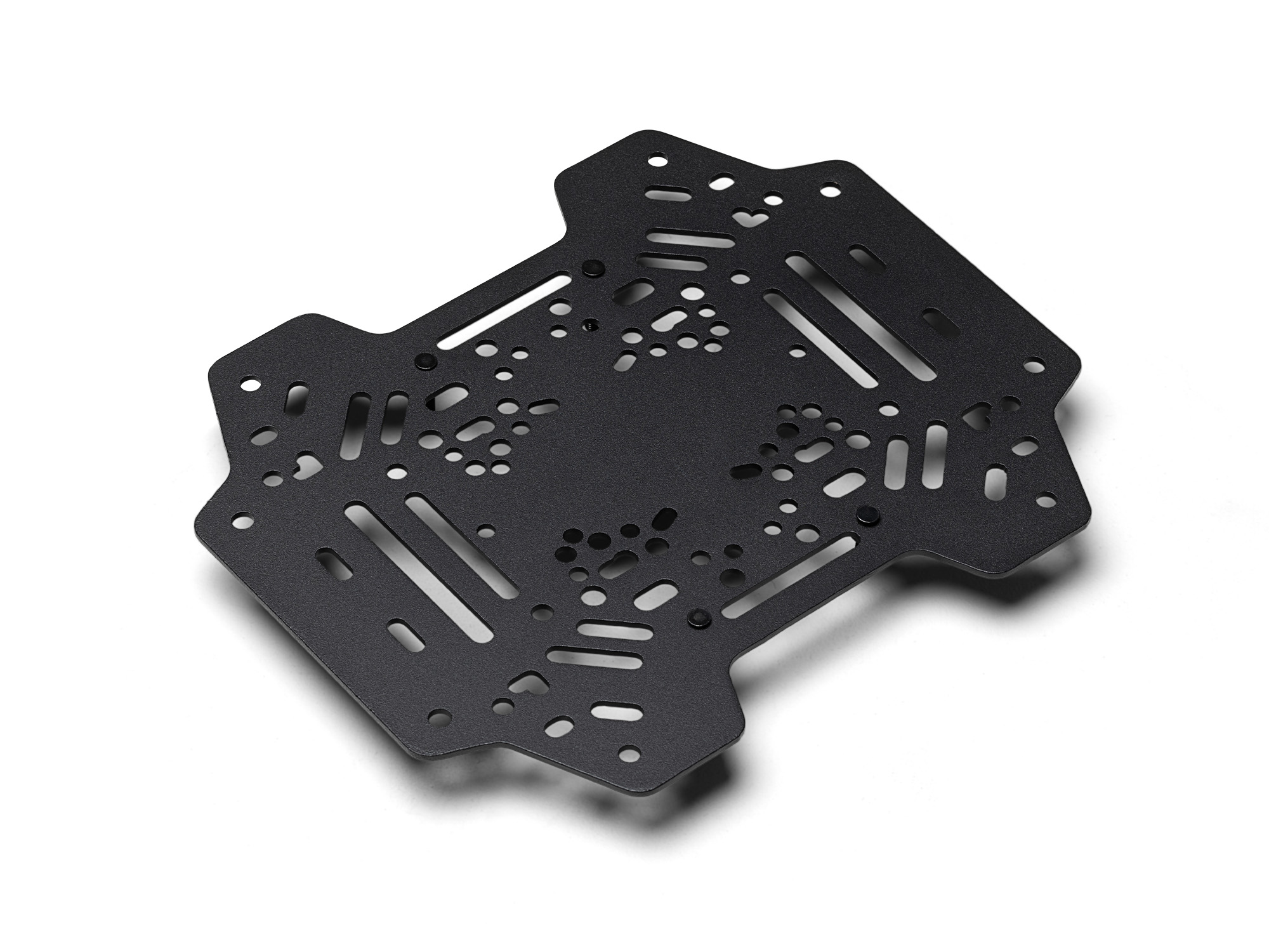 Una placa de metal negro con muchos agujeros y ranuras. Está sobre un fondo blanco.