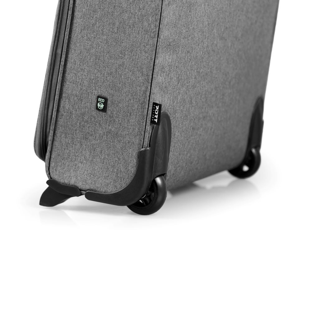 Primo piano di una valigia grigia con ruote nere. 'PORT Designs' e un simbolo eco visibili.