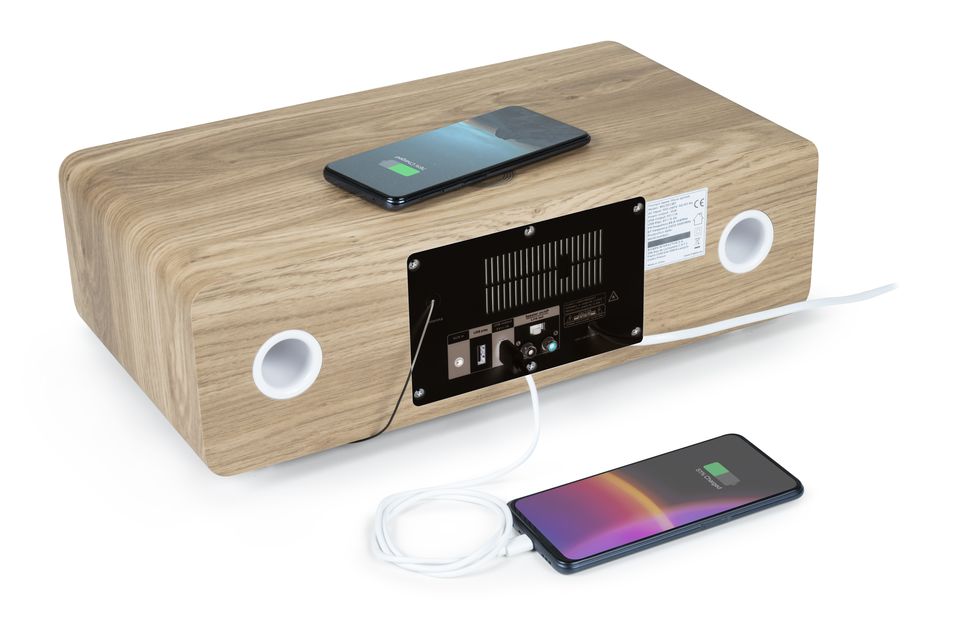 Drewniany głośnik z dwoma telefonami w trakcie ładowania. Białe kable łączą telefony z tyłem głośnika.