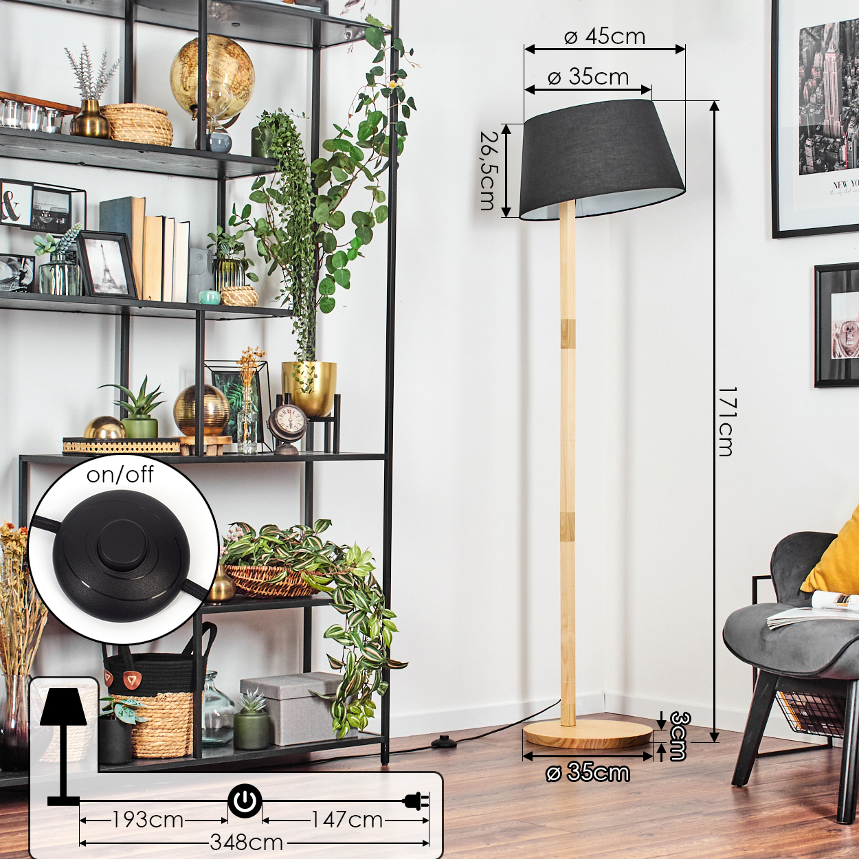 Eine Stehlampe mit schwarzem Lampenschirm und Holzständer. Links ein schwarzes Metallregal mit Dekorationen. Rechts ein Stuhl.