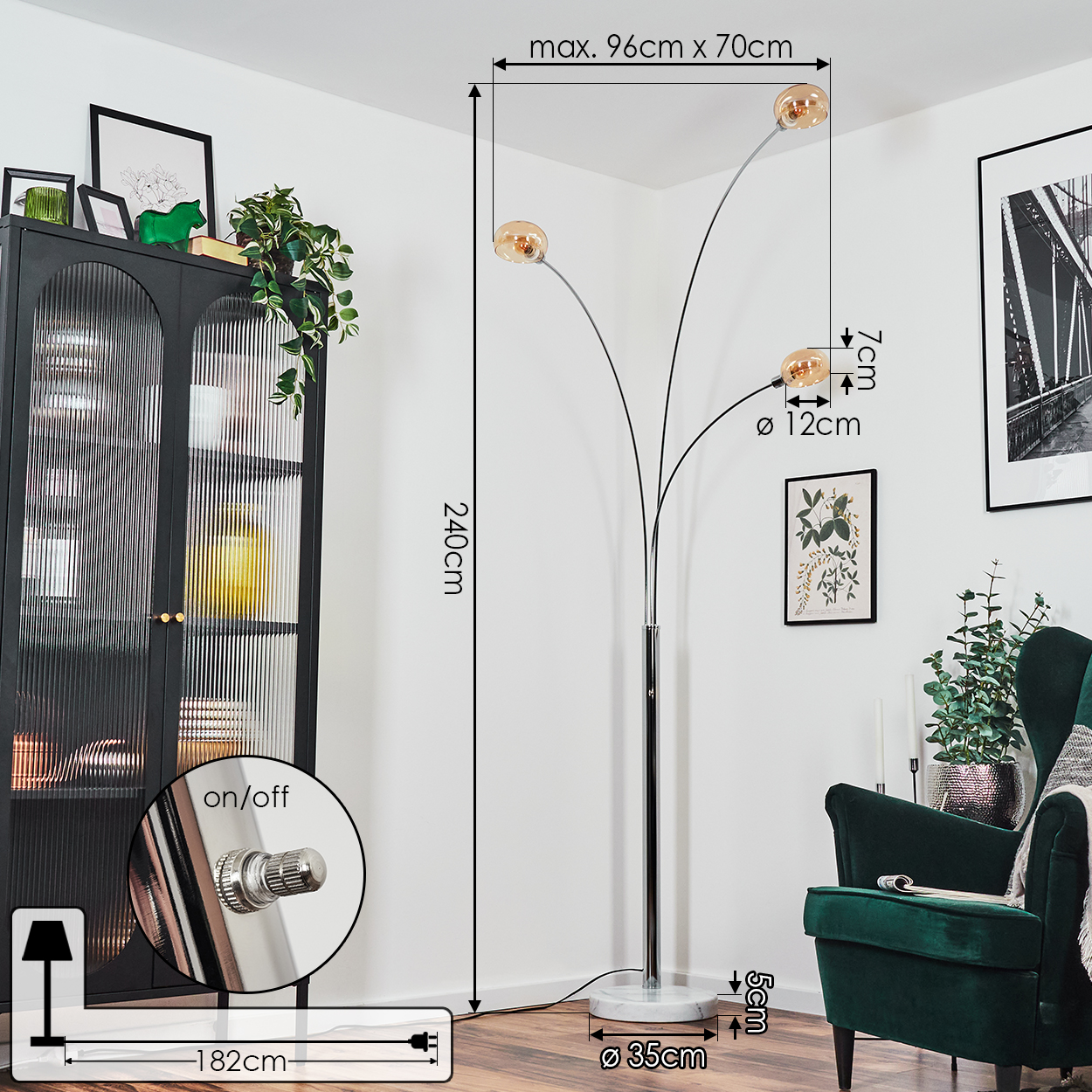 Eine moderne Stehlampe mit drei Lichtern steht in einem Raum. Ein dunkler Schrank, ein grüner Sessel und ein botanischer Druck sind ebenfalls vorhanden.