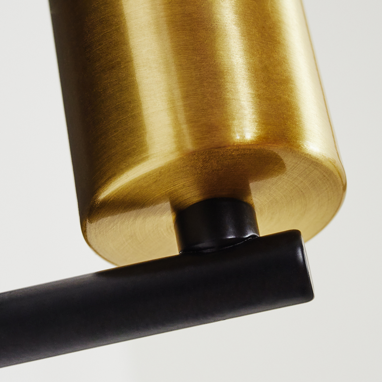 Nahaufnahme eines goldfarbenen zylindrischen Objekts, das mit einem schwarzen rechteckigen Balken verbunden ist. Der Hintergrund ist weiß.