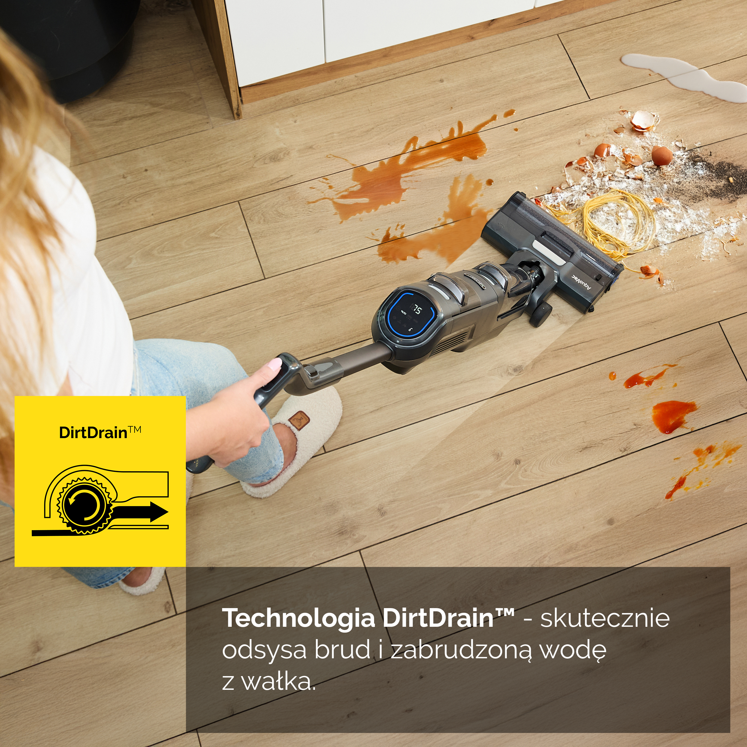Osoba odkurza brudną drewnianą podłogę. Rozlane jedzenie i płyn są na podłodze. W rogu znajduje się logo DirtDrain.