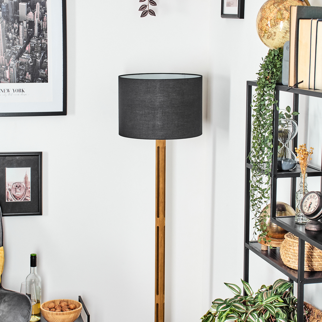 Ein Raum mit Stehlampe, Regalen mit Deko und einem New York-Bild an der Wand.