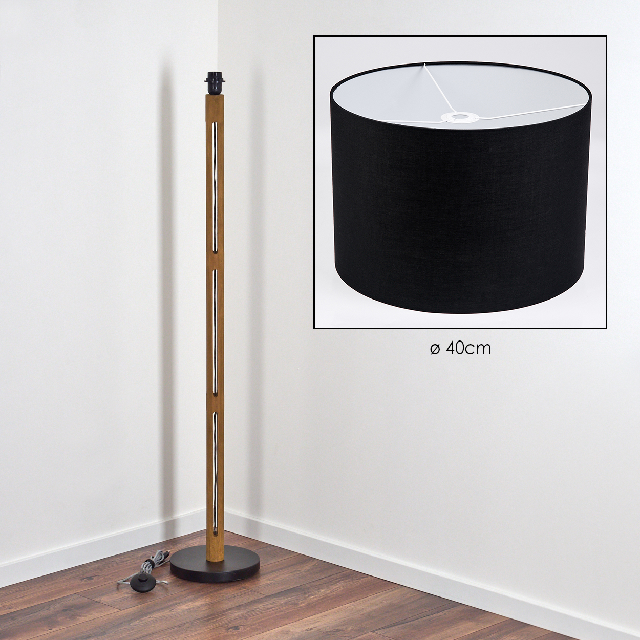 Eine hölzerne Stehlampe mit schwarzem Lampenschirm. Die Lampe steht in einer Ecke. Der Lampenschirm hat einen Durchmesser von 40 cm.
