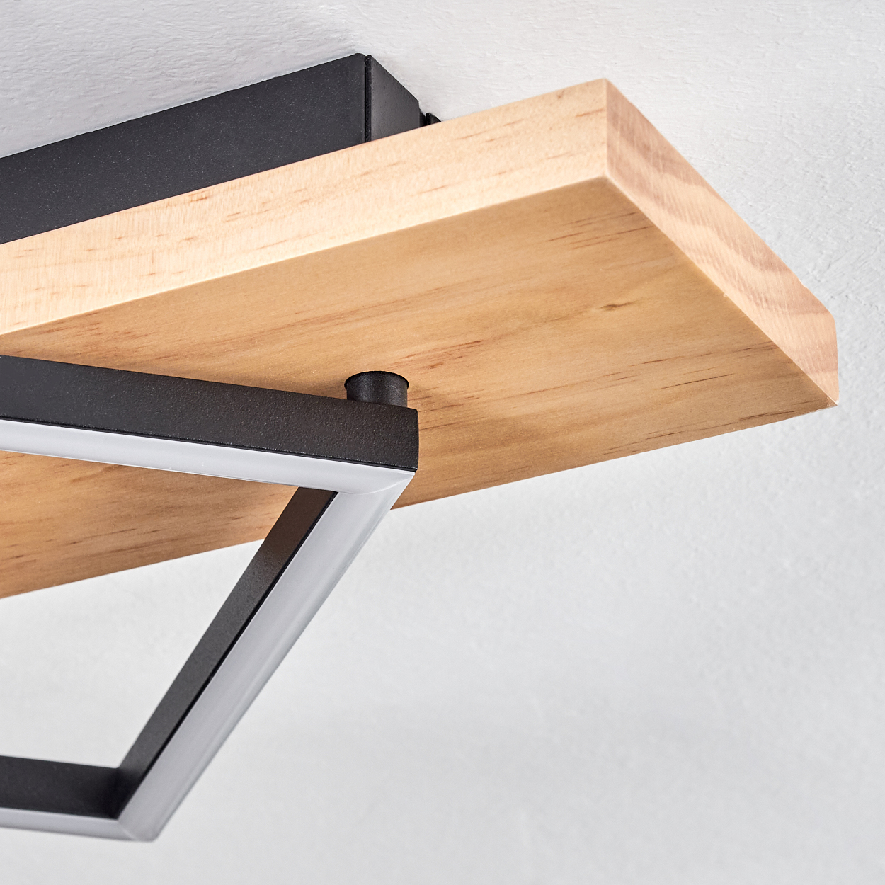 Holzregal an einer weißen Wand befestigt. Das Regal wird von einem schwarzen Metallrahmen getragen. Über dem Regal befindet sich eine schwarze Box.