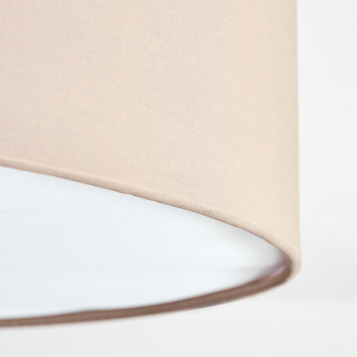 Nahaufnahme eines Lampenschirms. Der obere Teil ist beige und der untere weiß. Der Hintergrund ist ebenfalls weiß.