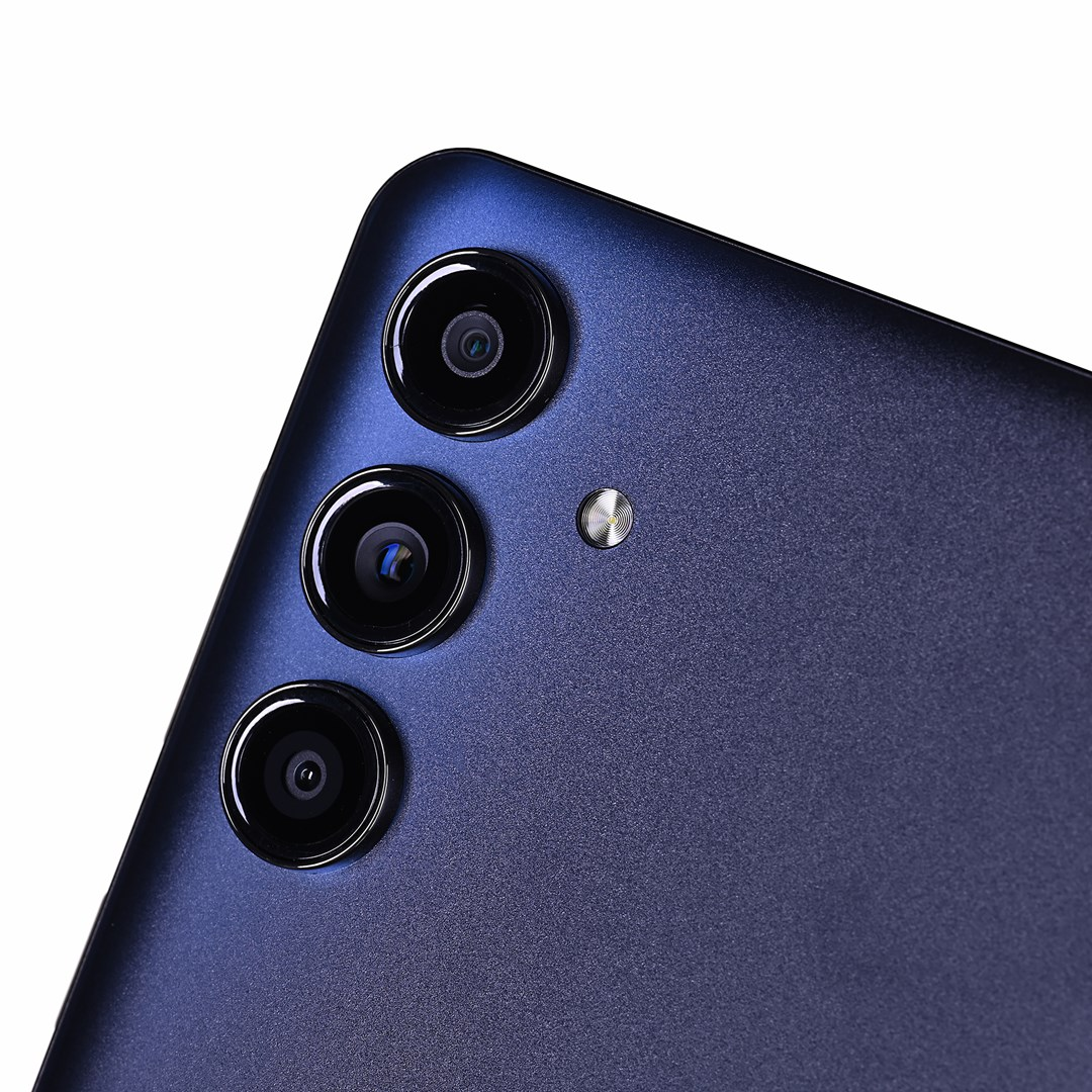 Zbliżenie tyłu niebieskiego smartfona. Widoczne są trzy obiektywy aparatu i lampa błyskowa. Powierzchnia ma teksturowane, matowe wykończenie.
