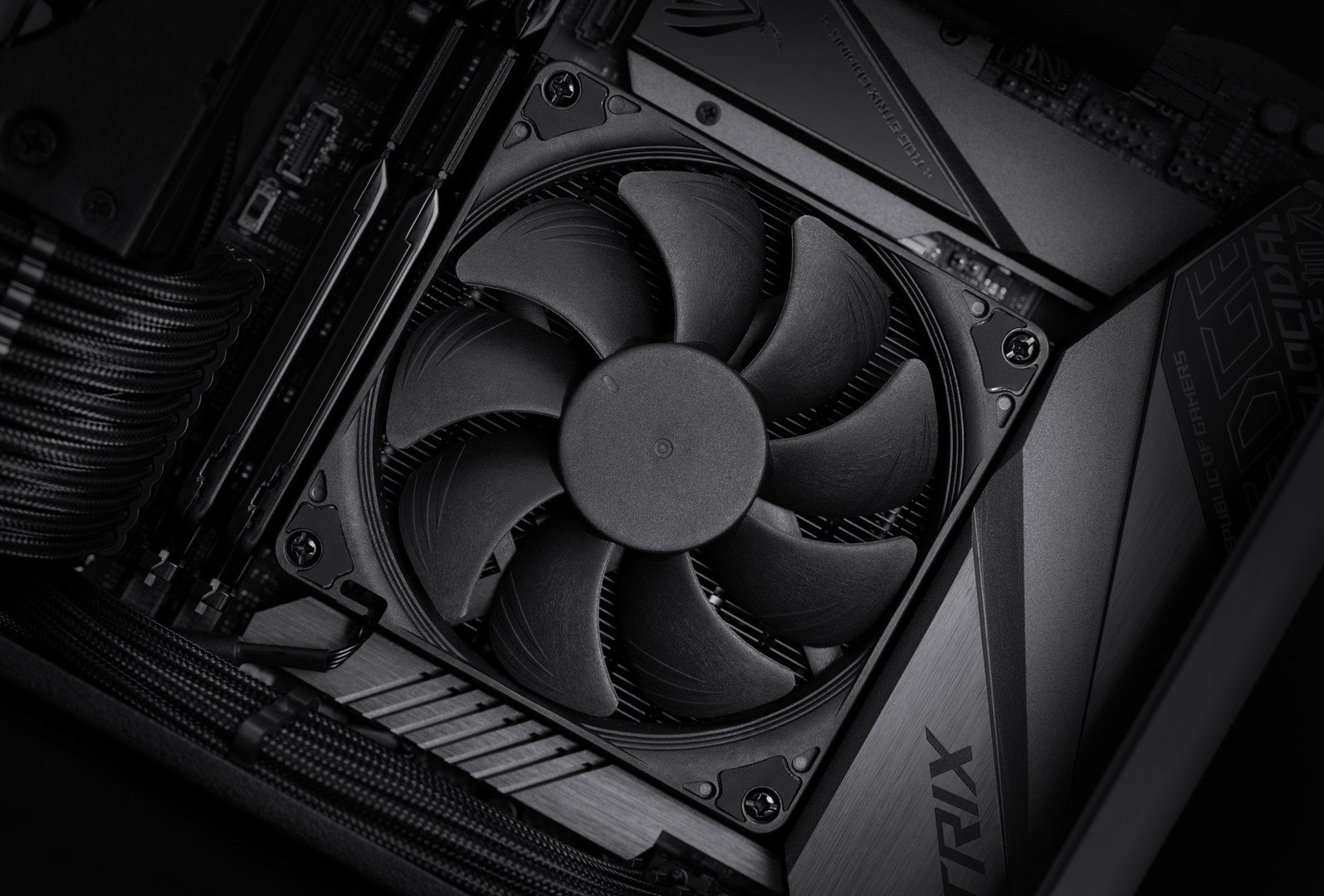 Zbliżenie czarnego wentylatora komputerowego na płycie głównej. Widoczne są łopaty wentylatora, śruby i szczegóły płytki drukowanej.