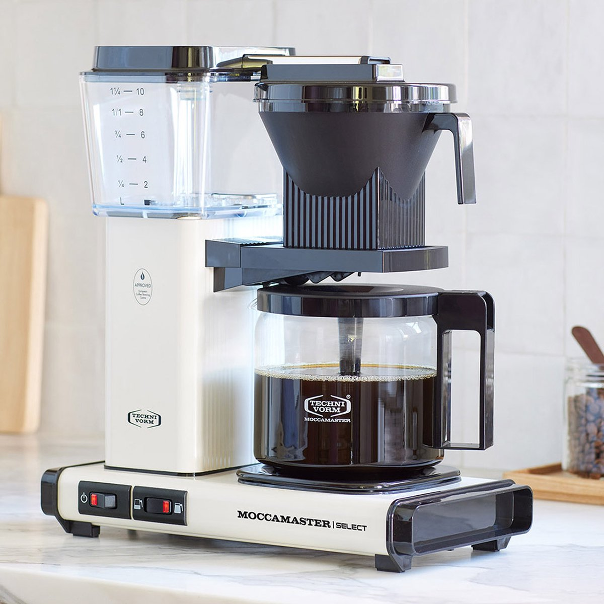Biało-czarny ekspres do kawy Moccamaster. Posiada szklany dzbanek z kawą, filtr i zbiornik na wodę.