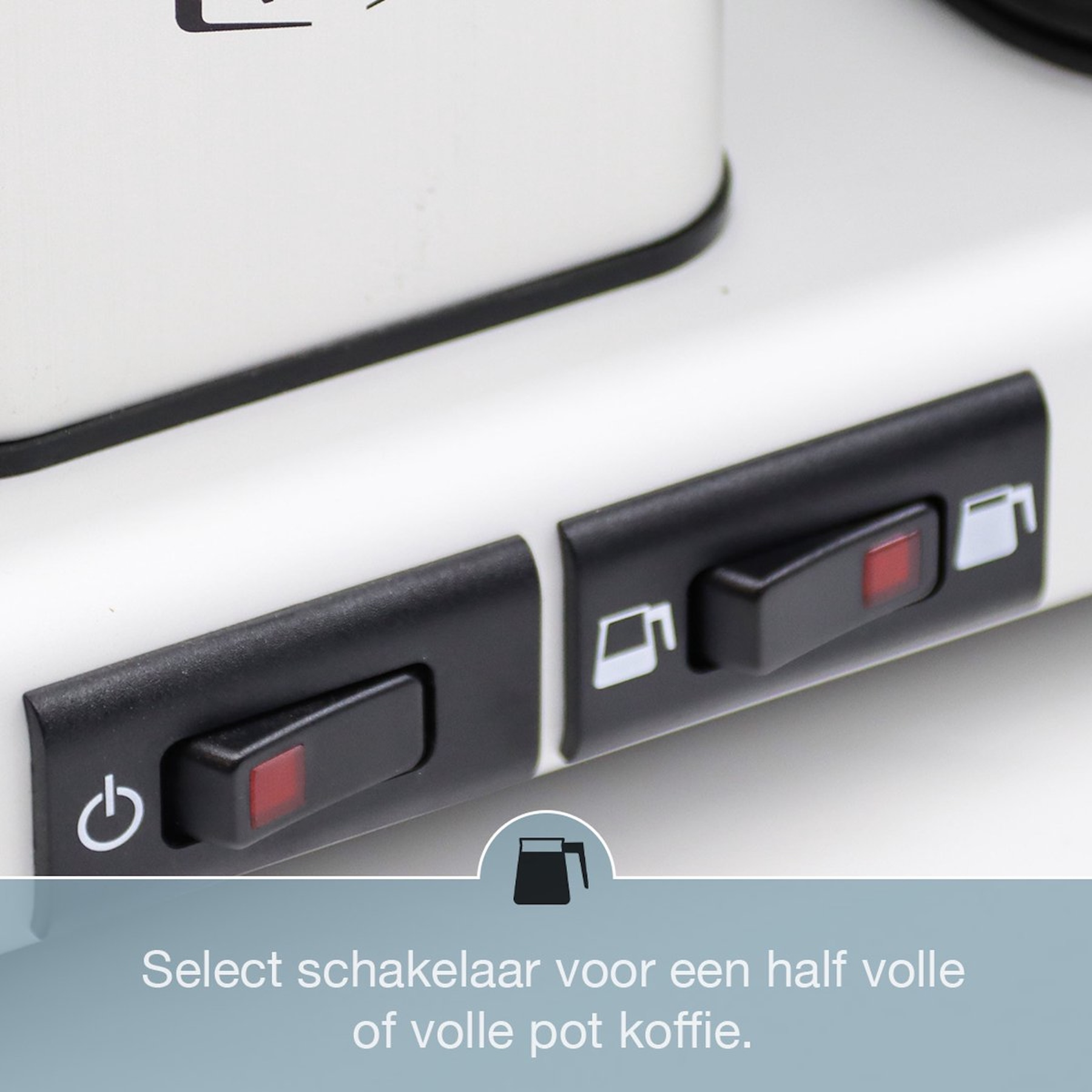 Zbliżenie ekspresu do kawy z czarnymi przełącznikami. Jeden ma symbol zasilania, drugi symbol dzbanka do kawy.