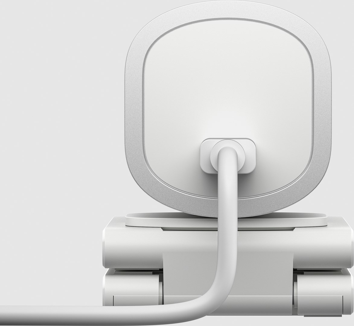 Zbliżenie białego urządzenia z zaokrągloną górą i srebrną obwódką. Z tyłu wpięty jest biały kabel. Tło jest białe.