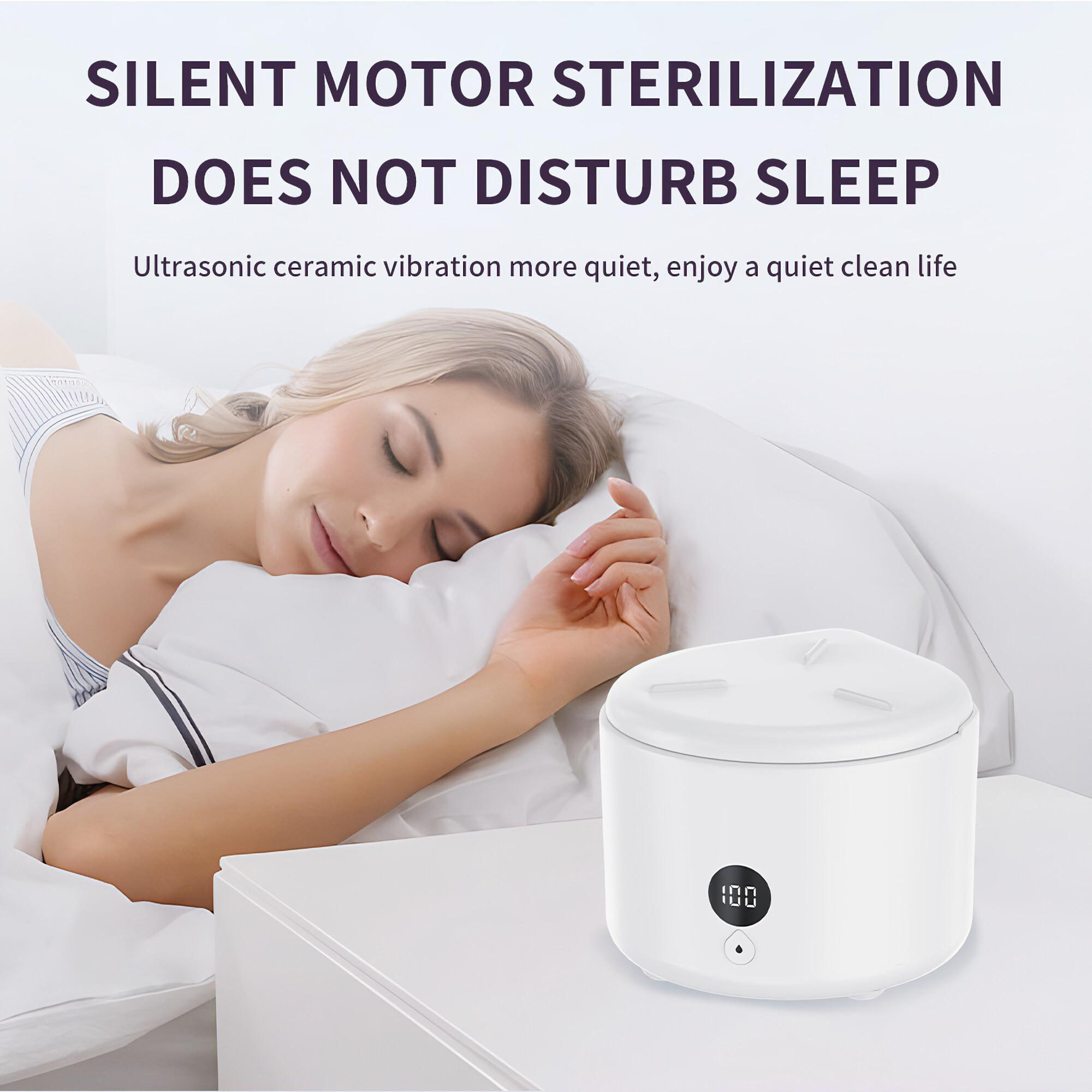 Eine Frau schläft im Bett. Auf einem Nachttisch steht ein weißes Sterilisationsgerät mit Digitalanzeige.