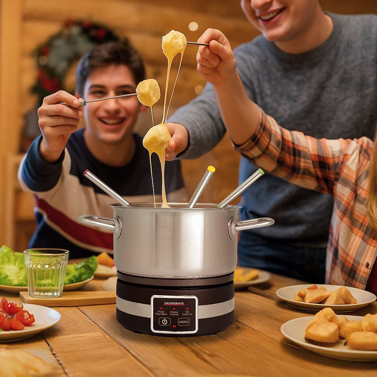 Menschen genießen Fondue. Käse tropft von Brot, das von Gabeln gehalten wird. Ein Fonduetopf steht auf einem Holztisch, umgeben von Essen und Menschen.
