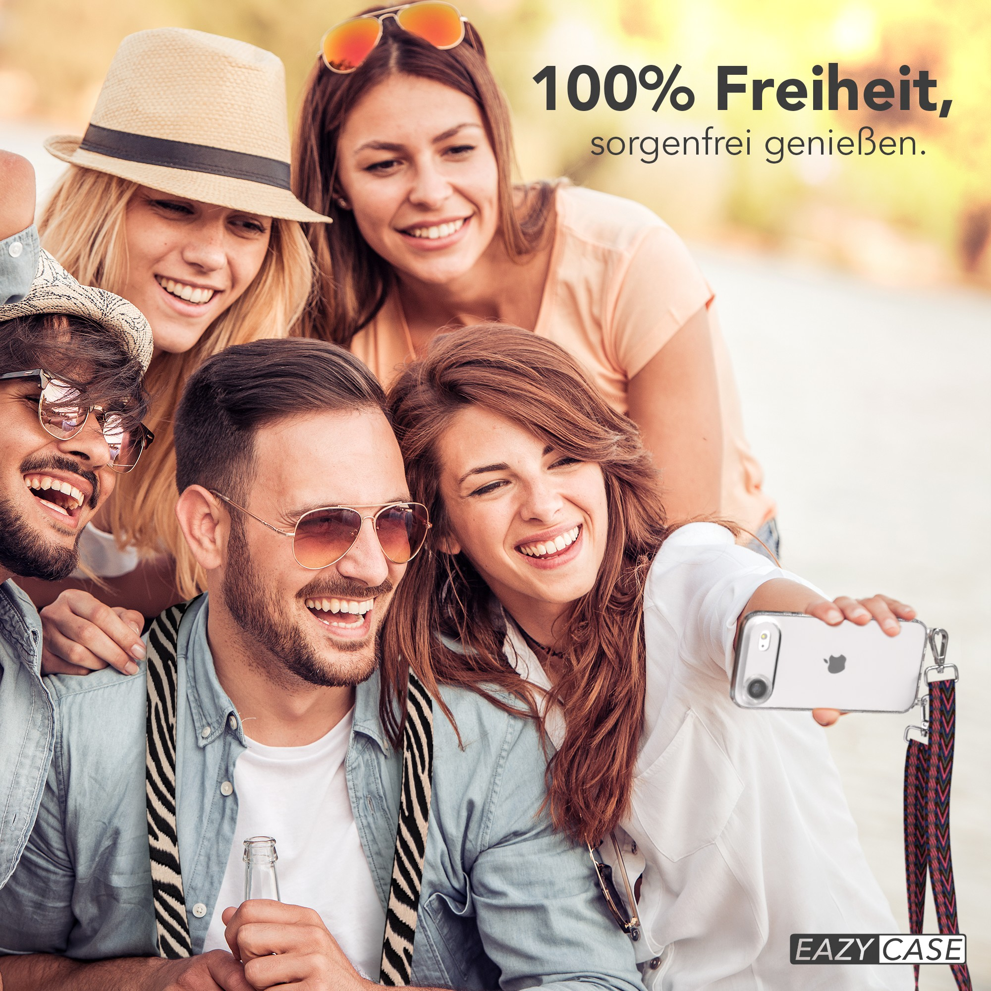 Gruppe von Freunden, die ein Selfie machen, alle lächeln. Einer hält ein Handy mit einem Umhängeband. Text: '100% Freiheit, sorglos genießen'.