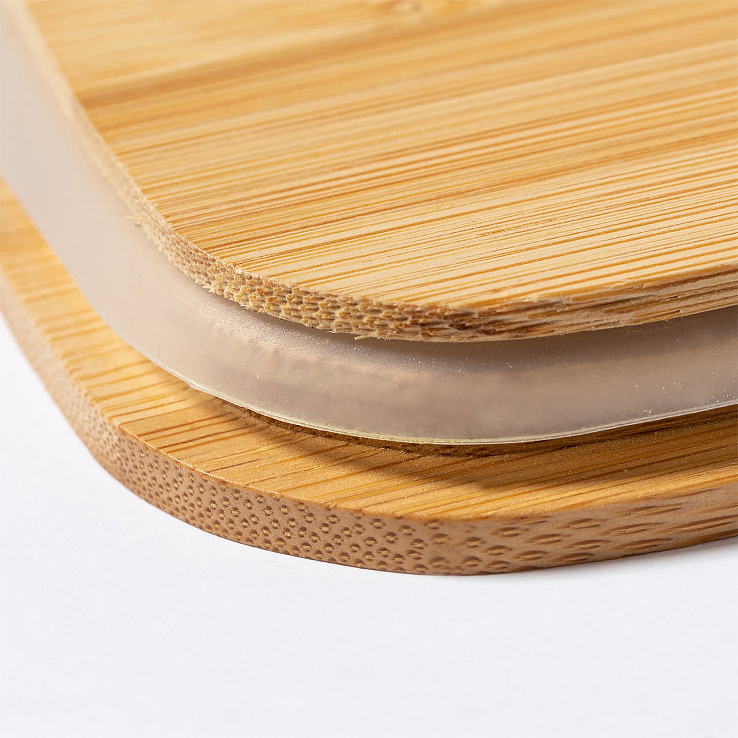 Primer plano de una tapa de madera con un anillo de plástico transparente. La madera es marrón claro con vetas visibles. Fondo blanco.