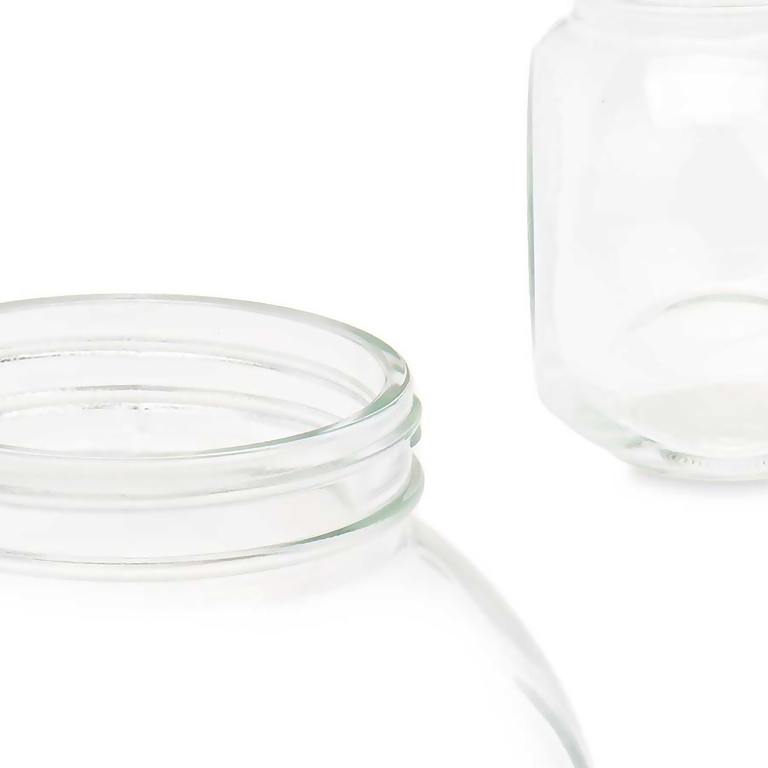 Primer plano de dos frascos de vidrio transparente sobre fondo blanco. El borde de un frasco está enfocado, el otro desenfocado.