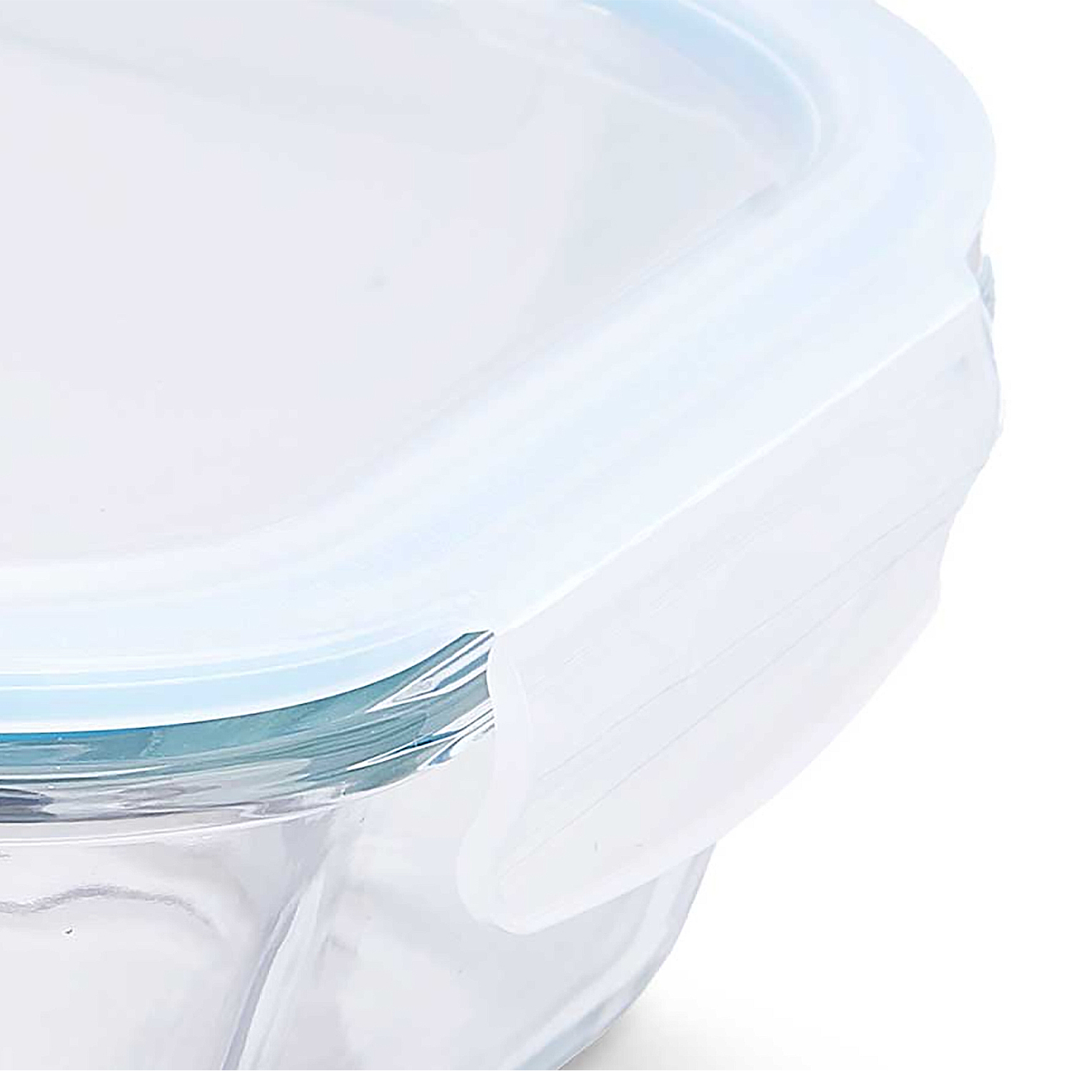 Primer plano de un recipiente de vidrio para alimentos con tapa blanca. La tapa tiene un borde azul y un clip de plástico blanco.