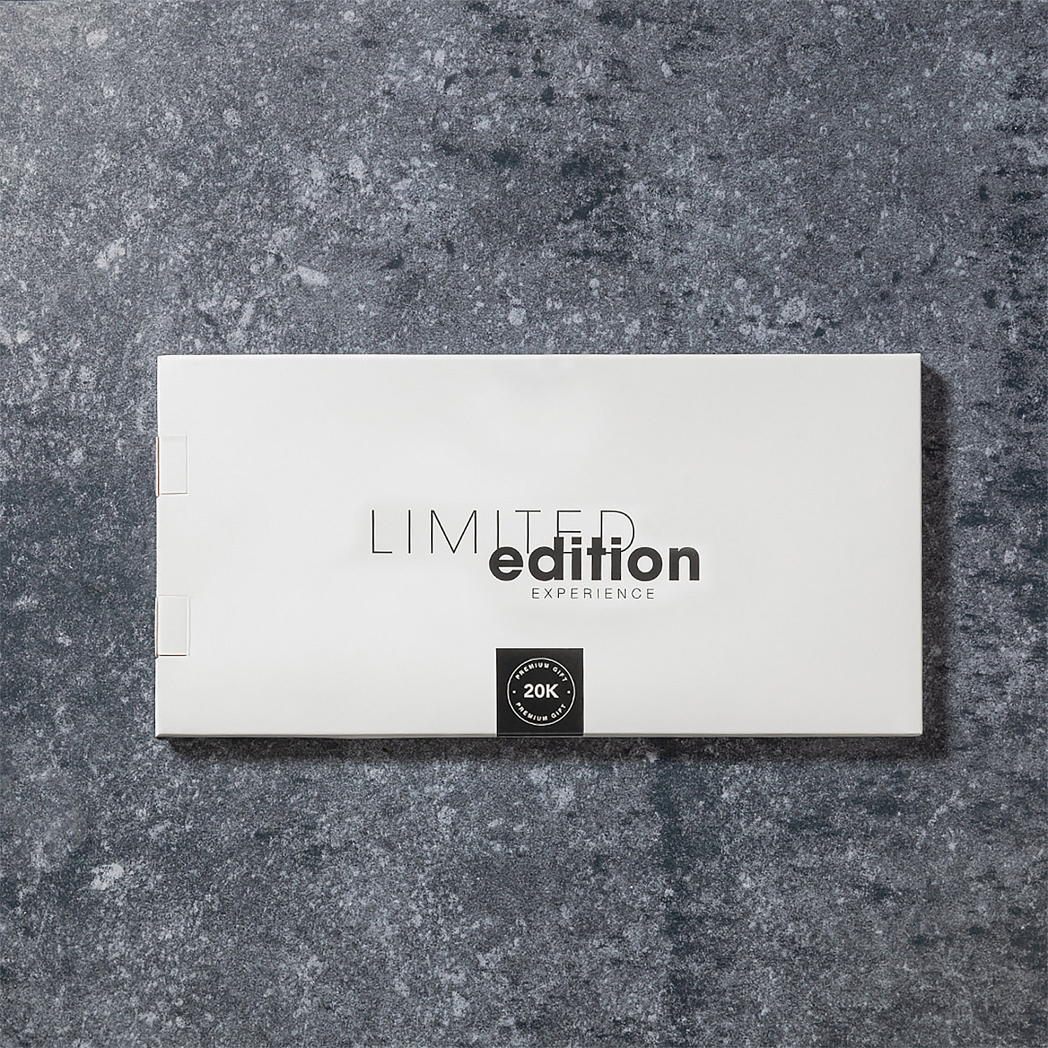 Una scatola bianca con 'LIMITED edition EXPERIENCE' su una superficie grigia strutturata. Un adesivo nero recita 'PREMIUM GIFT 20K'.