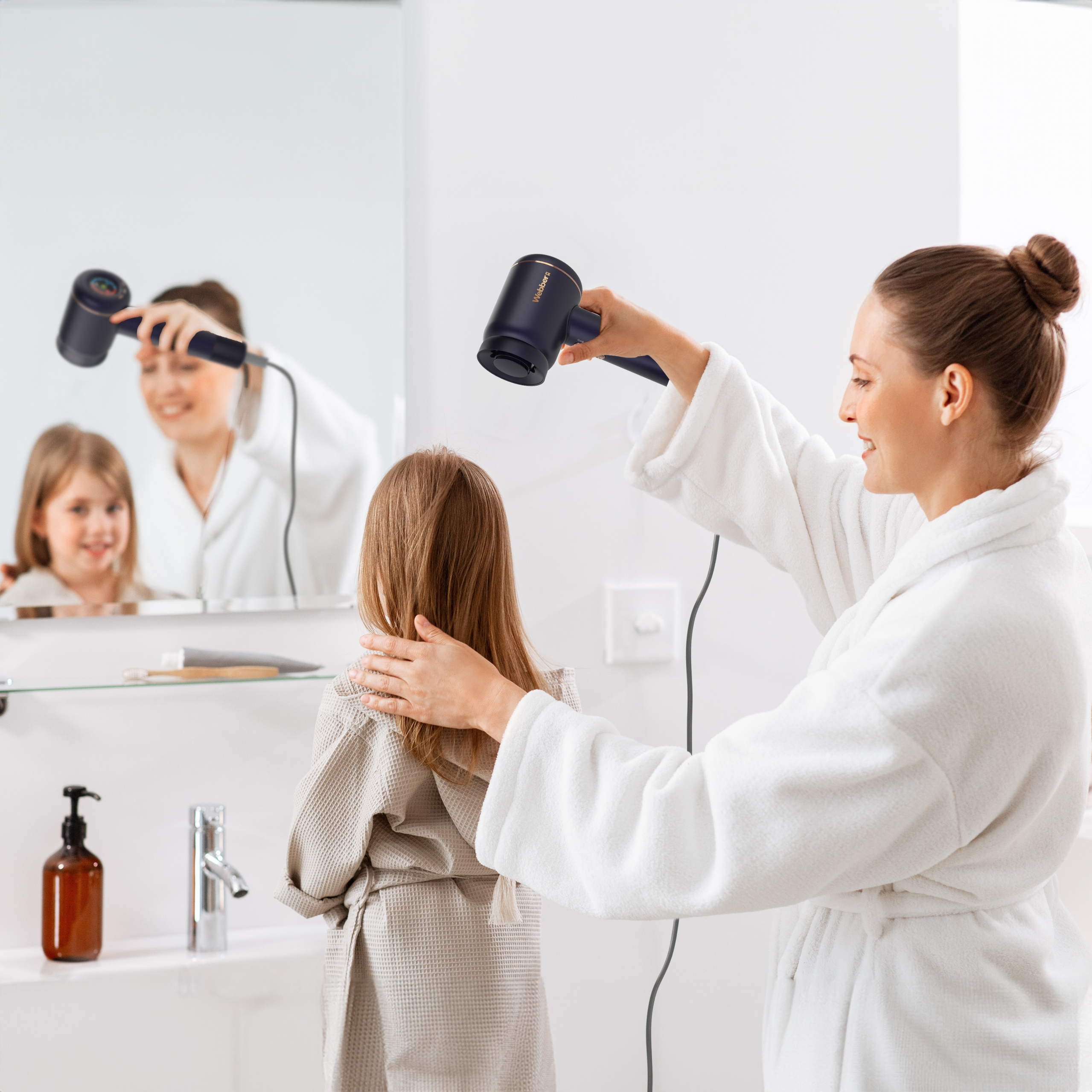 Kobieta suszy włosy dziewczynki suszarką w łazience. Lustro odbija ich wizerunki.