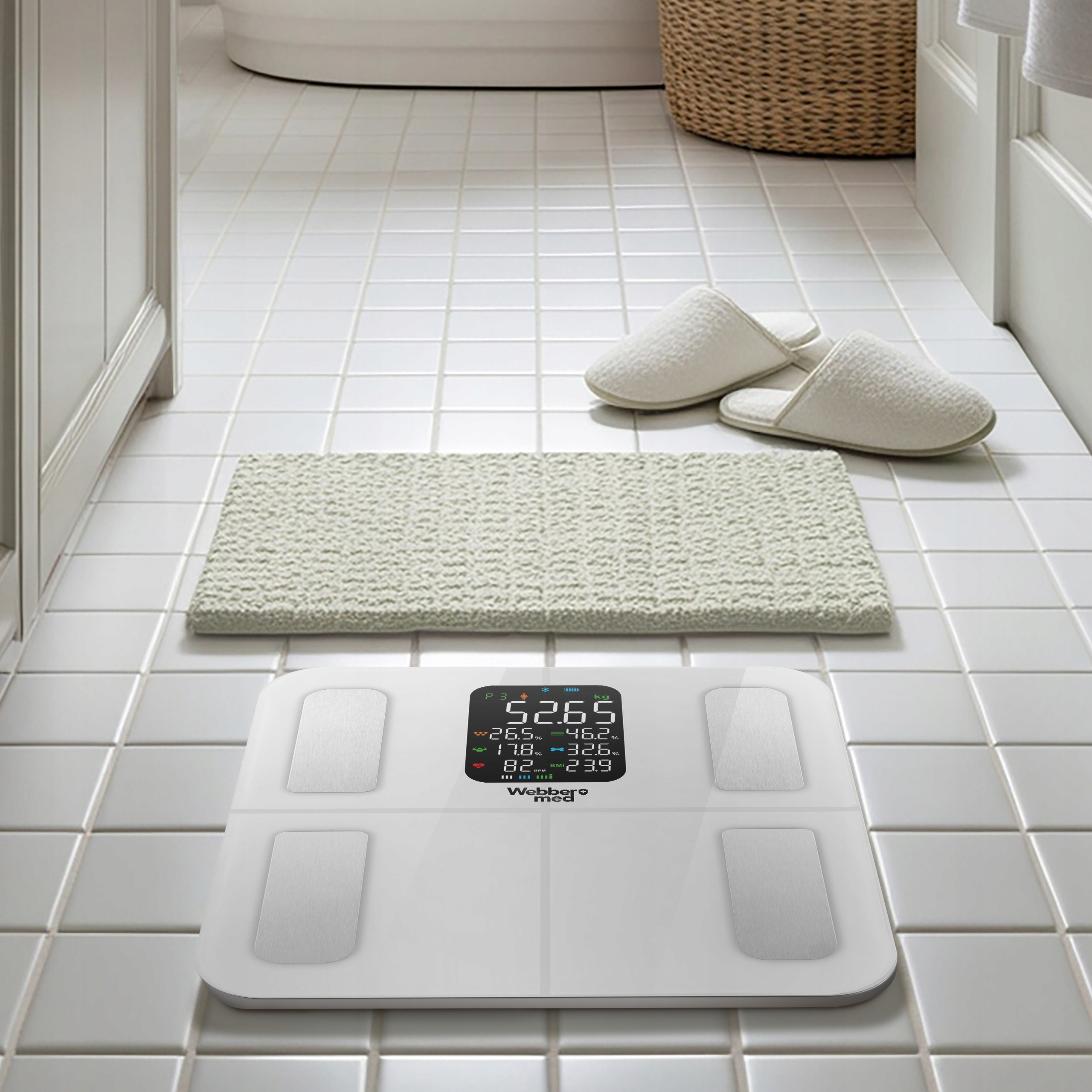 Scena łazienkowa. Waga pokazuje wagę. Kapcie i dywanik leżą w pobliżu. Widoczne są białe płytki i wiklinowy kosz.