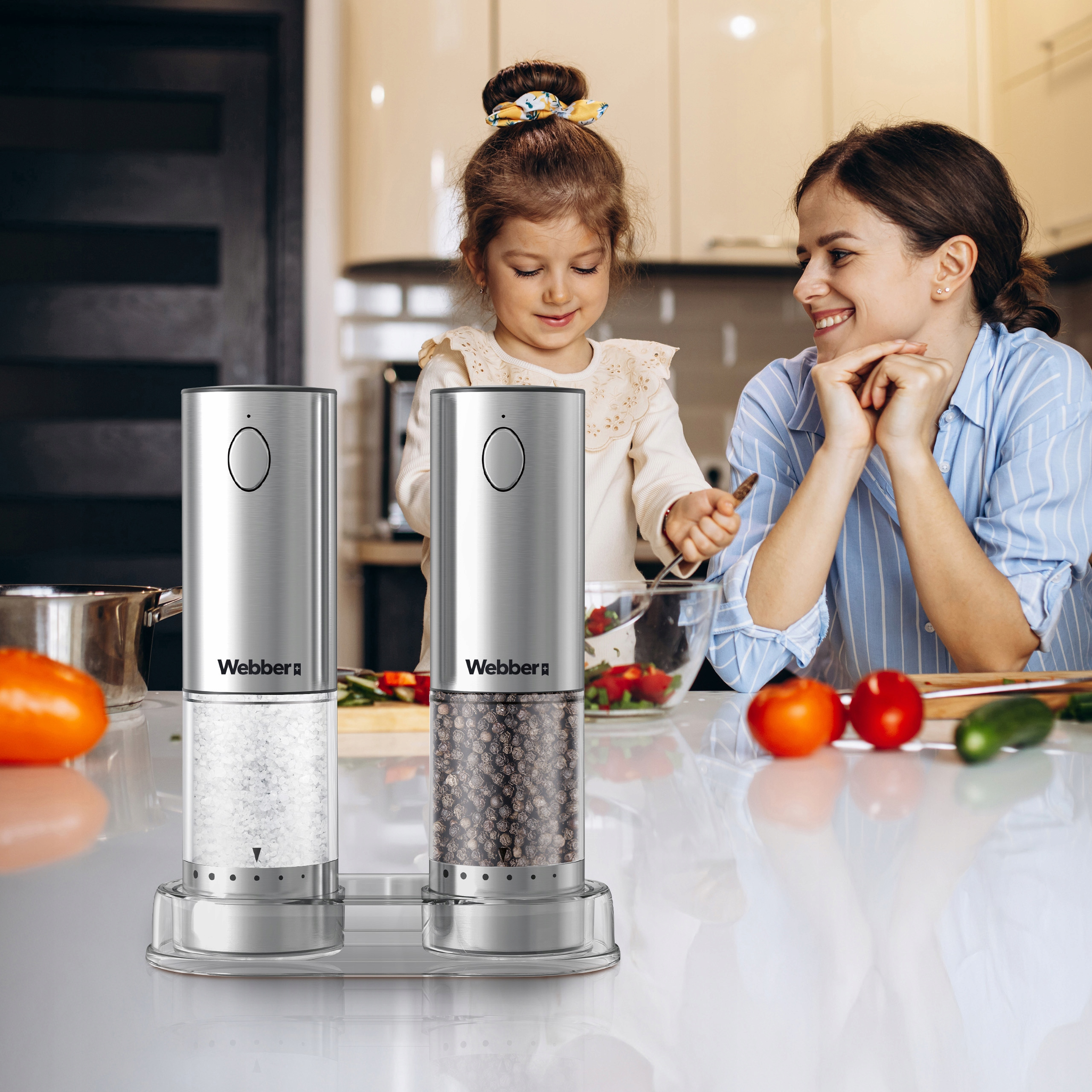 Kobieta i dziecko gotują w kuchni, młynki do soli i pieprzu, warzywa i uśmiechnięta kobieta.