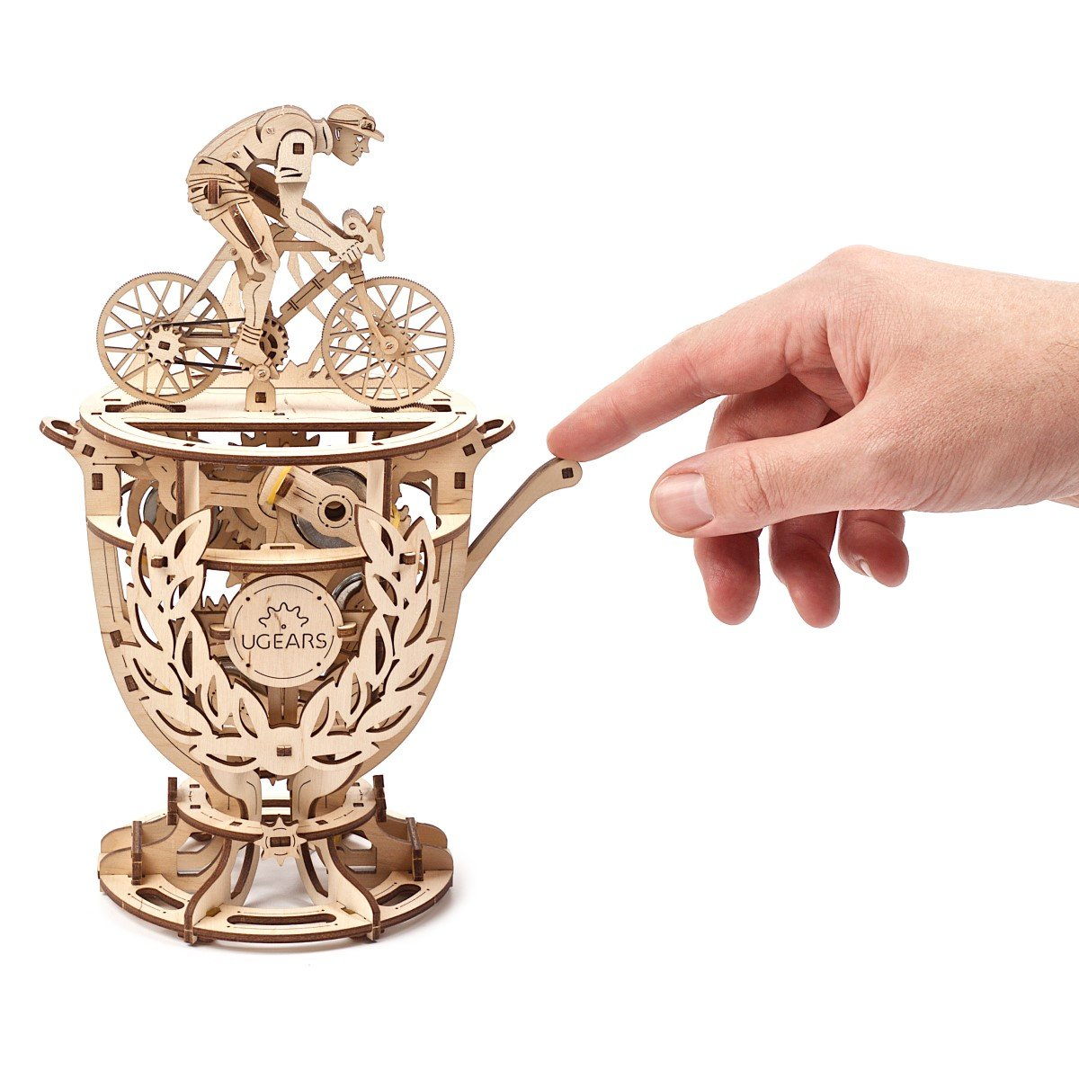 Drewniany model roweru na trofeum. Dłoń wskazuje na niego. Model jest jasnobrązowy z marką UGEARS.