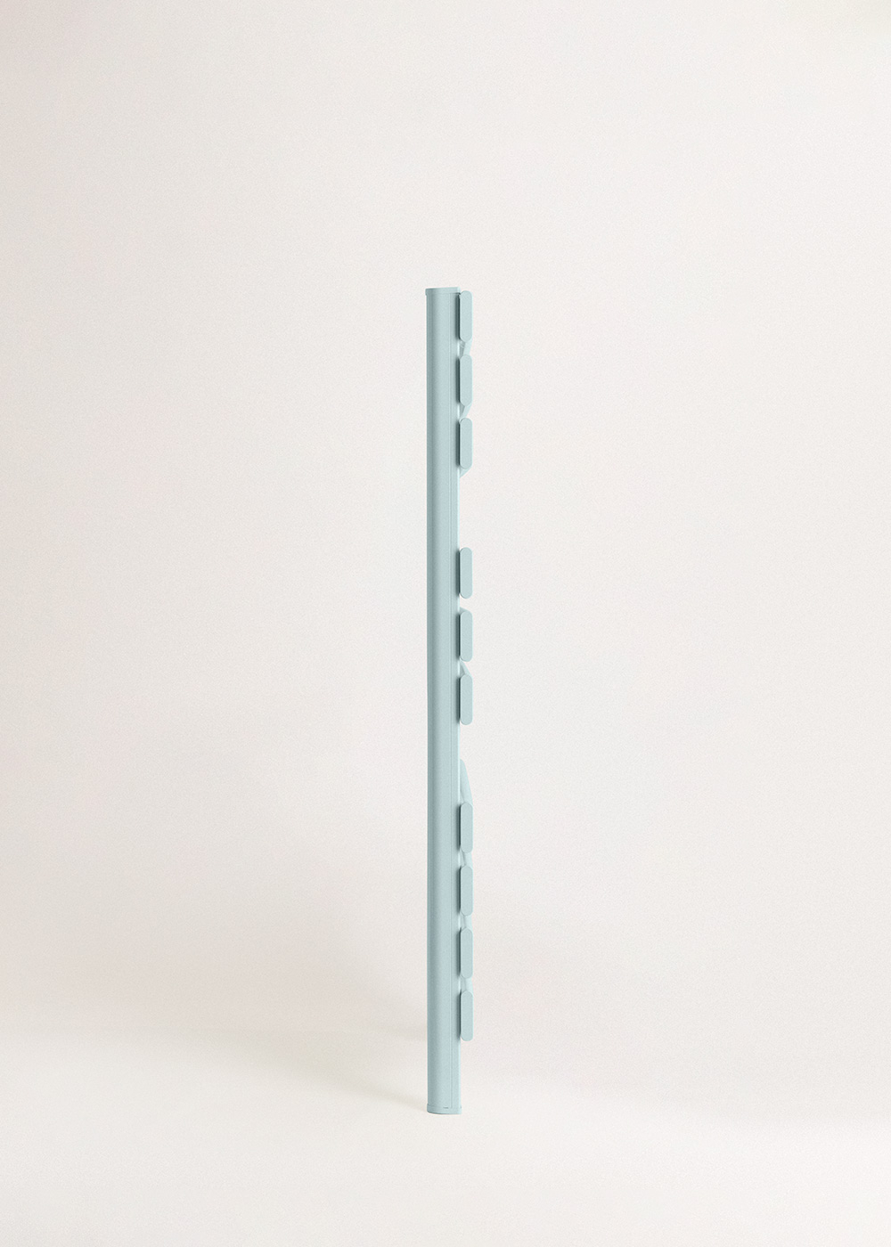 Una barra de metal vertical azul claro con recortes rectangulares en un lado. El fondo es blanco roto.